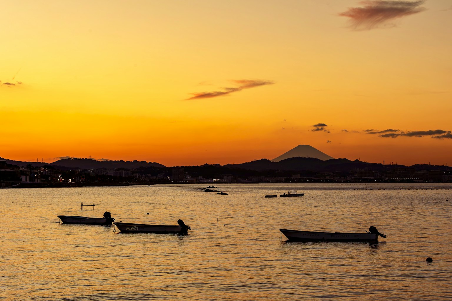 夕陽下海面的小船，背景是富士山