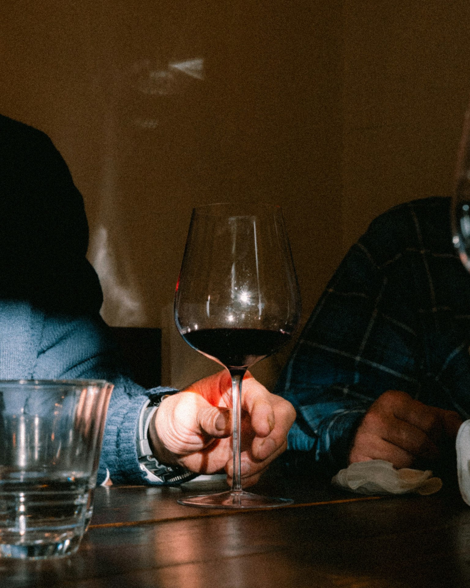 ワイングラスを持つ手とテーブルの上のグラス