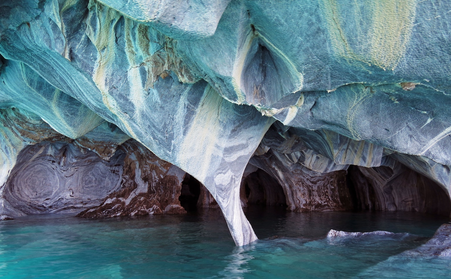 Innenansicht einer blauen Höhle mit beeindruckenden Felsformationen und Wasserreflexionen
