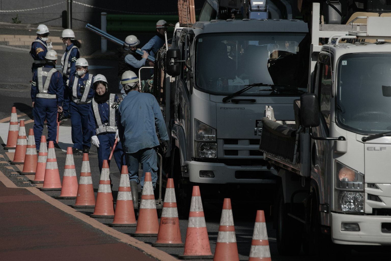Construction workers near traffic cones working on a street