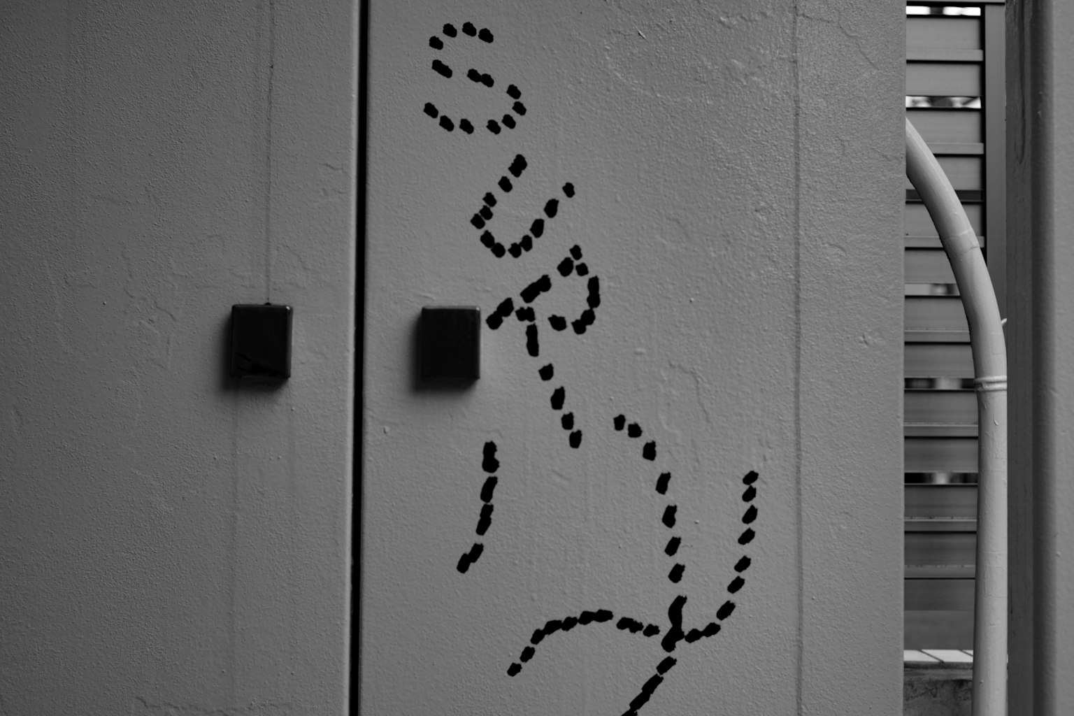 黒い背景に白い文字で「SURY」と描かれたドアの一部