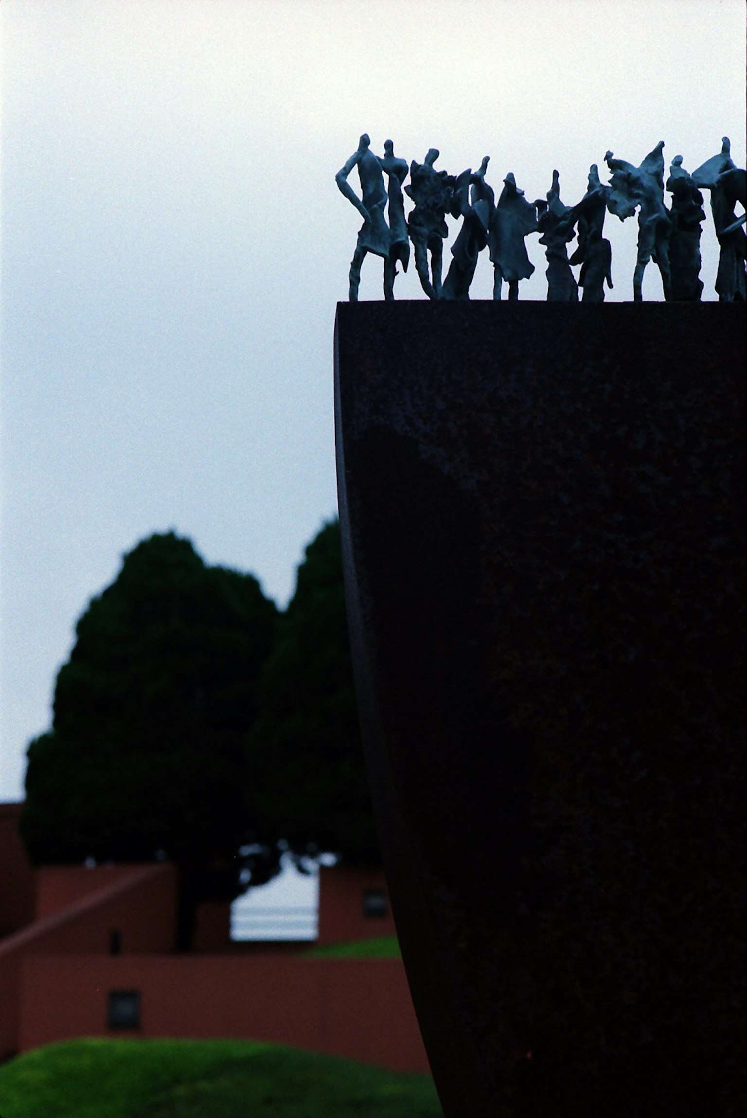 Gruppe von Figuren auf einer Skulptur mit einem grünen Hügel im Hintergrund