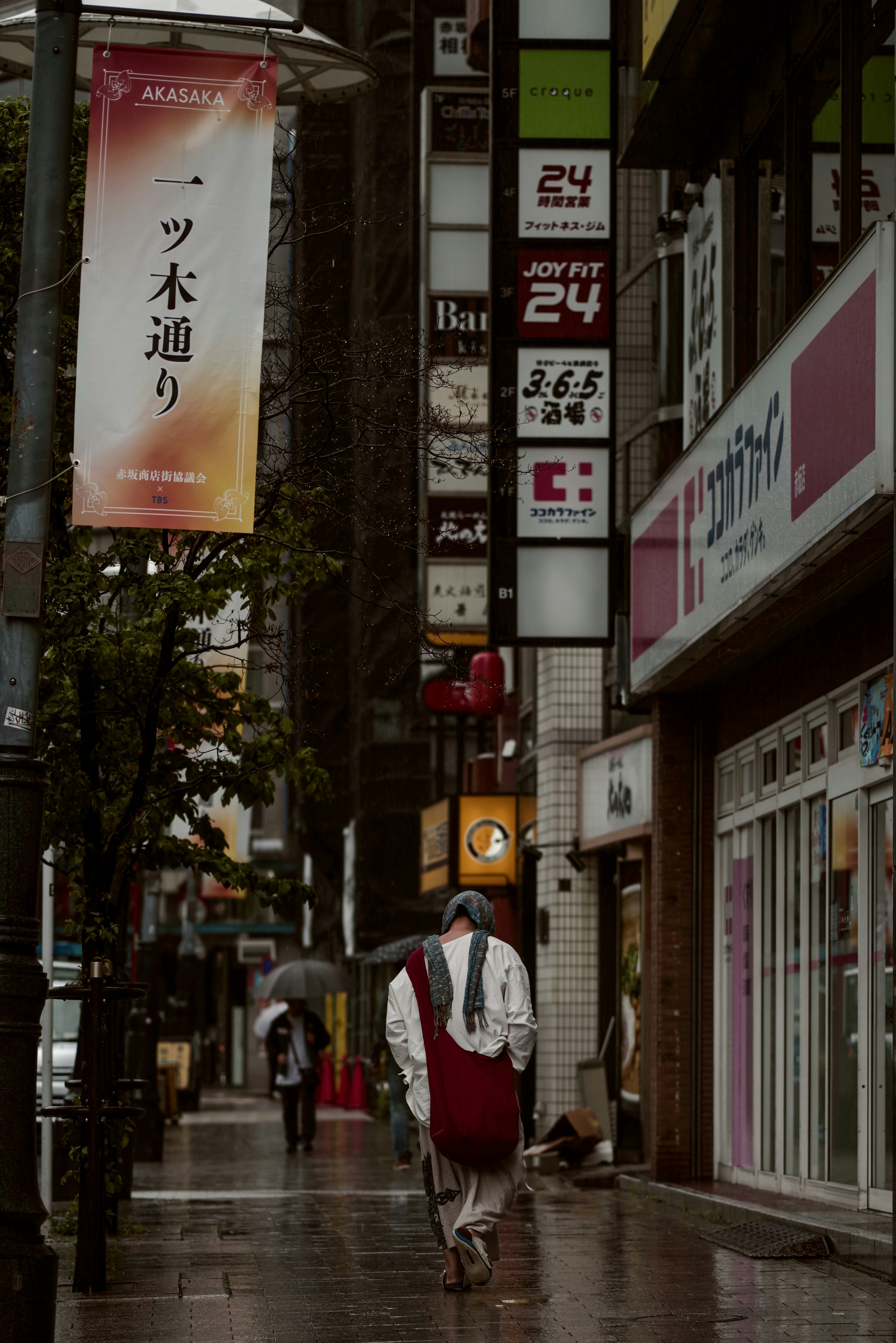 Rainy alley in Akasaka, Tokyo with storefront signs and pedestrians