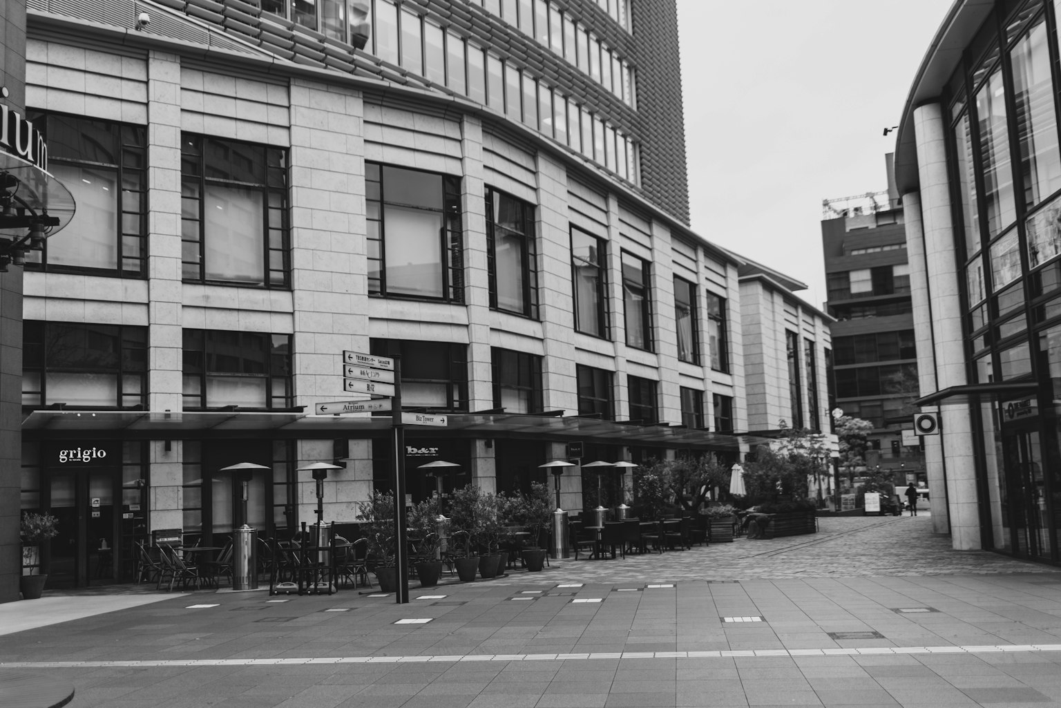 Schwarzweißbild einer Stadtlandschaft mit einer Caféterrasse und modernen Gebäuden
