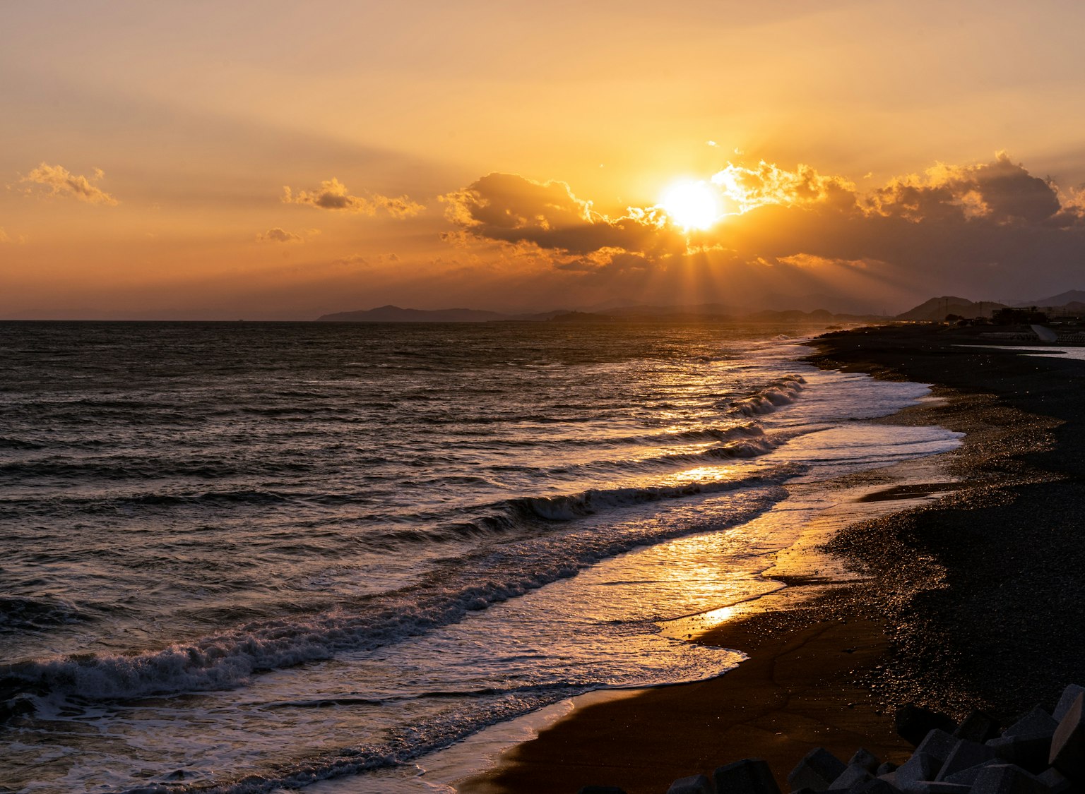 Pemandangan matahari terbenam yang indah di atas lautan ombak menyapu pantai