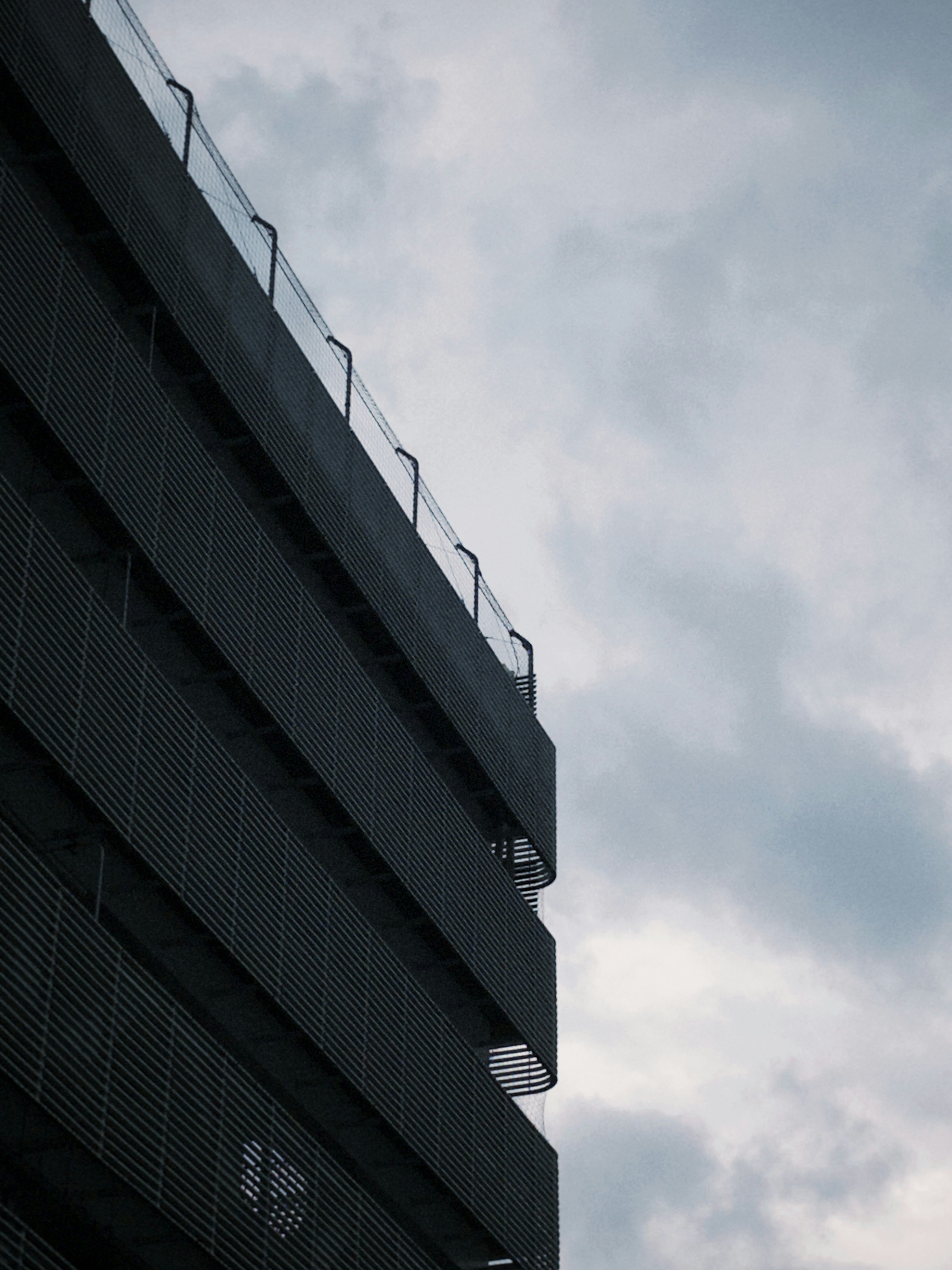 斜めに伸びる建物の外壁と空の雲