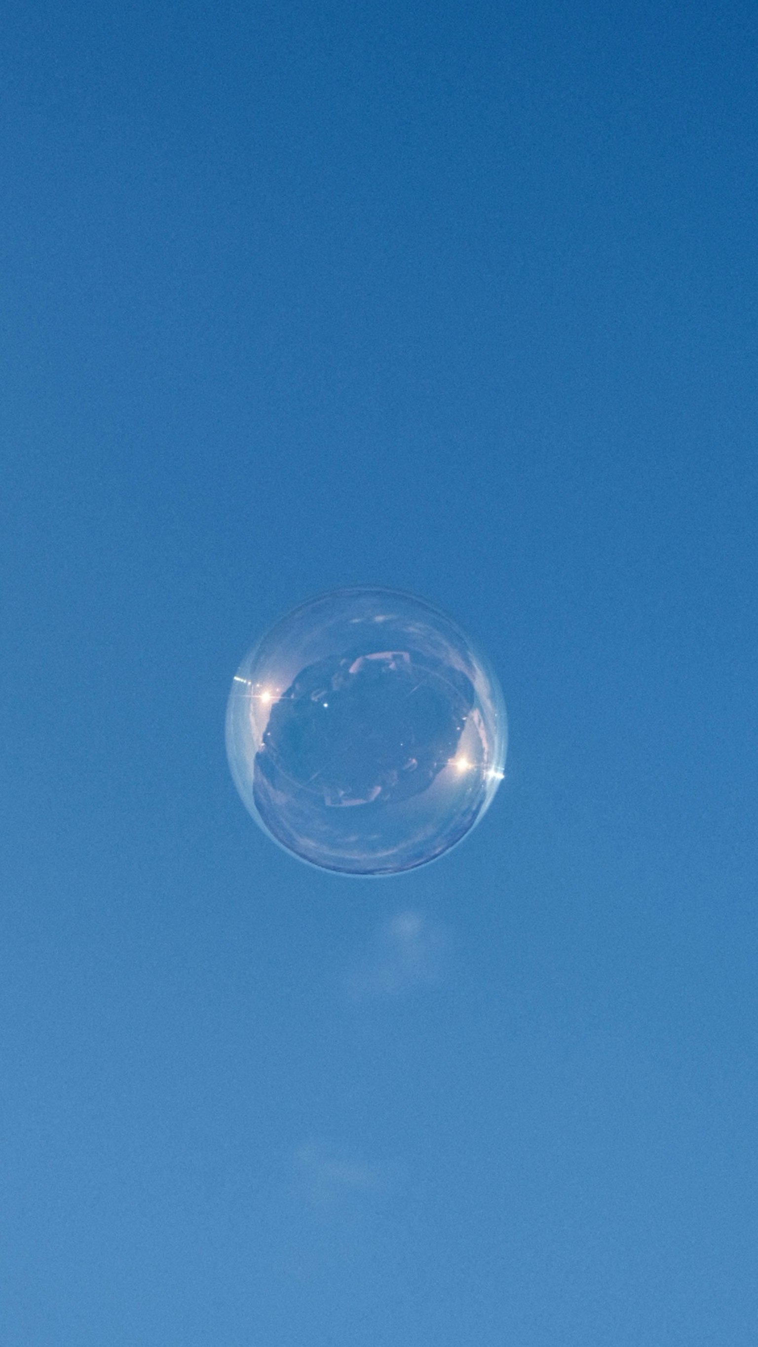 Eine transparente Seifenblase schwebt im blauen Himmel