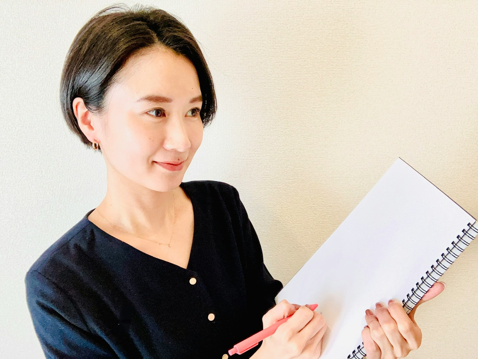 펜으로 스케치북에 쓰고 있는 여성