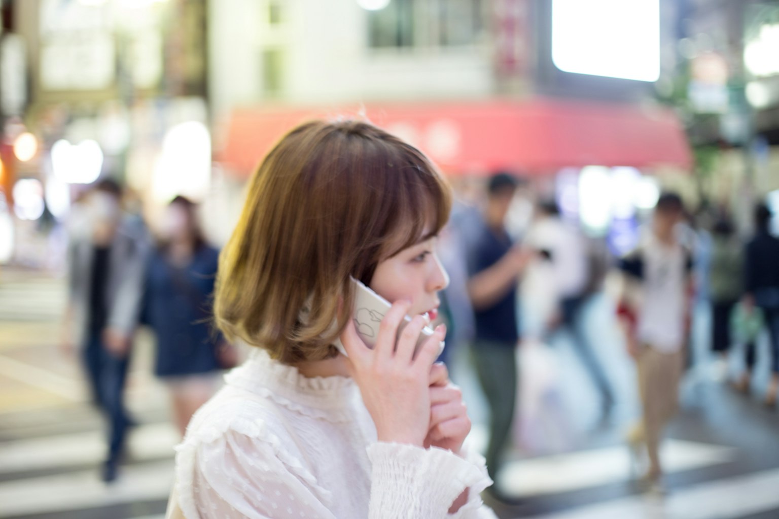 Profile of a woman talking on her phone in a bustling city at night