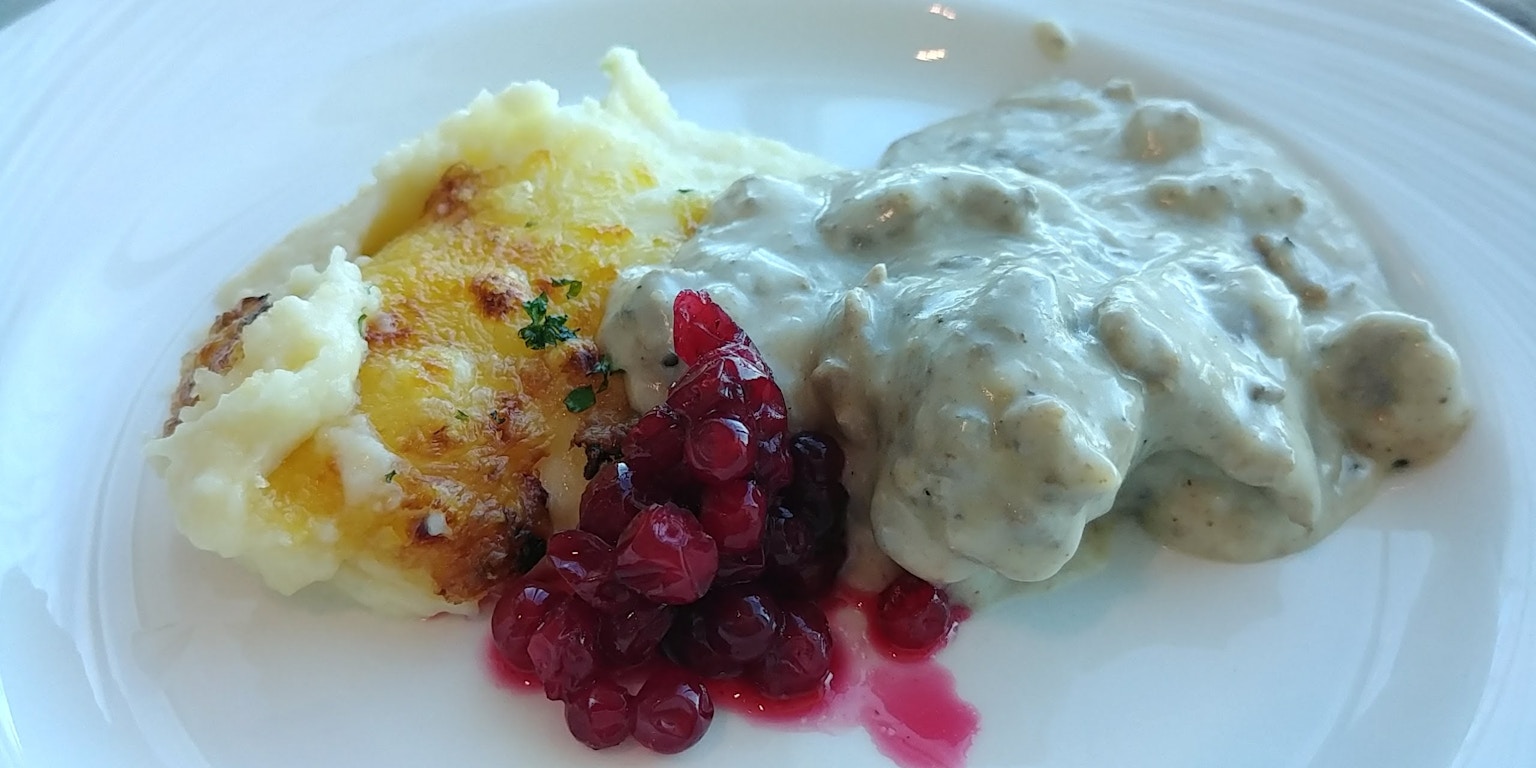 Piring dengan saus krim di atas daging, kentang tumbuk, dan saus beri merah