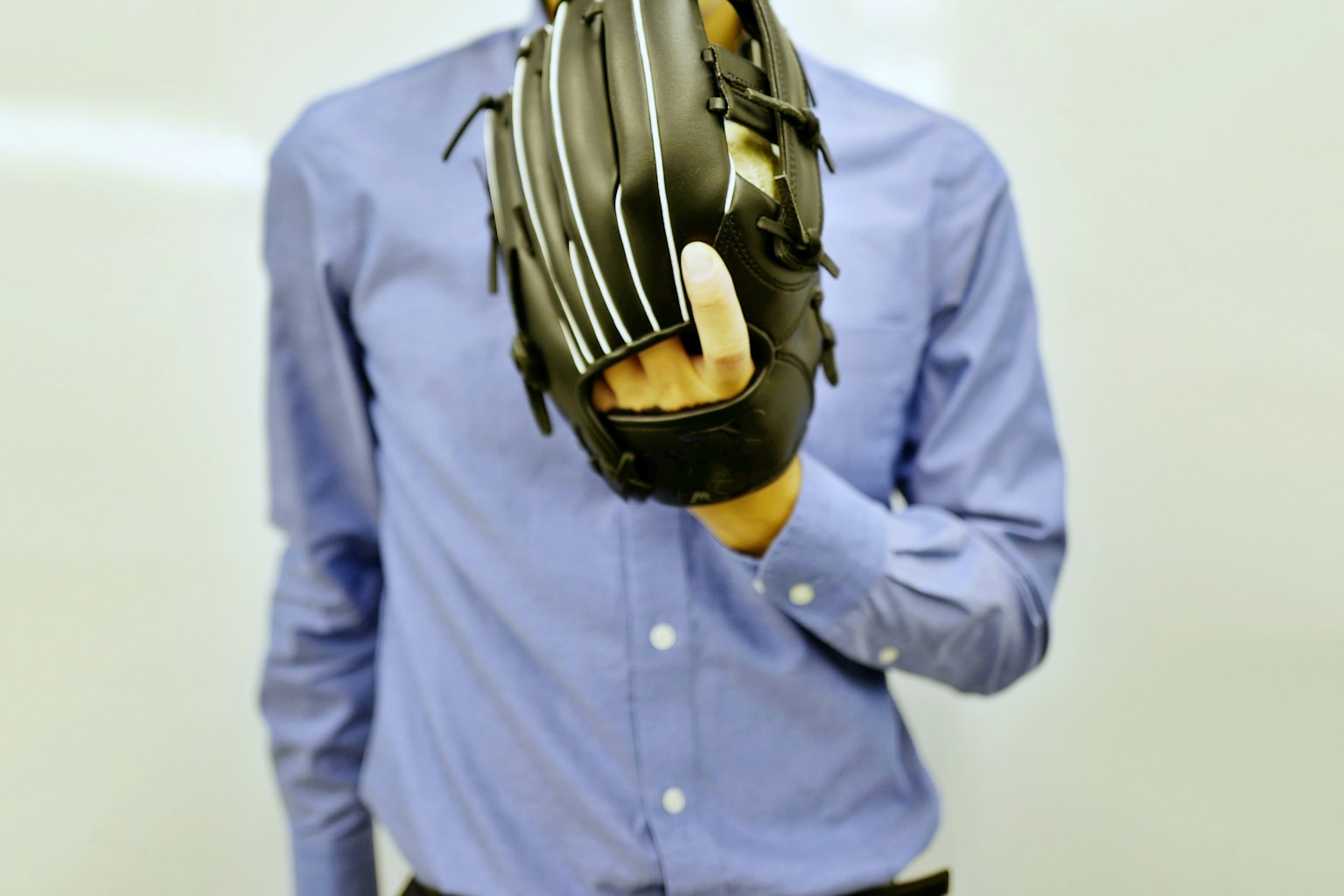 Persona in camicia blu che tiene un guanto da baseball con le dita estese