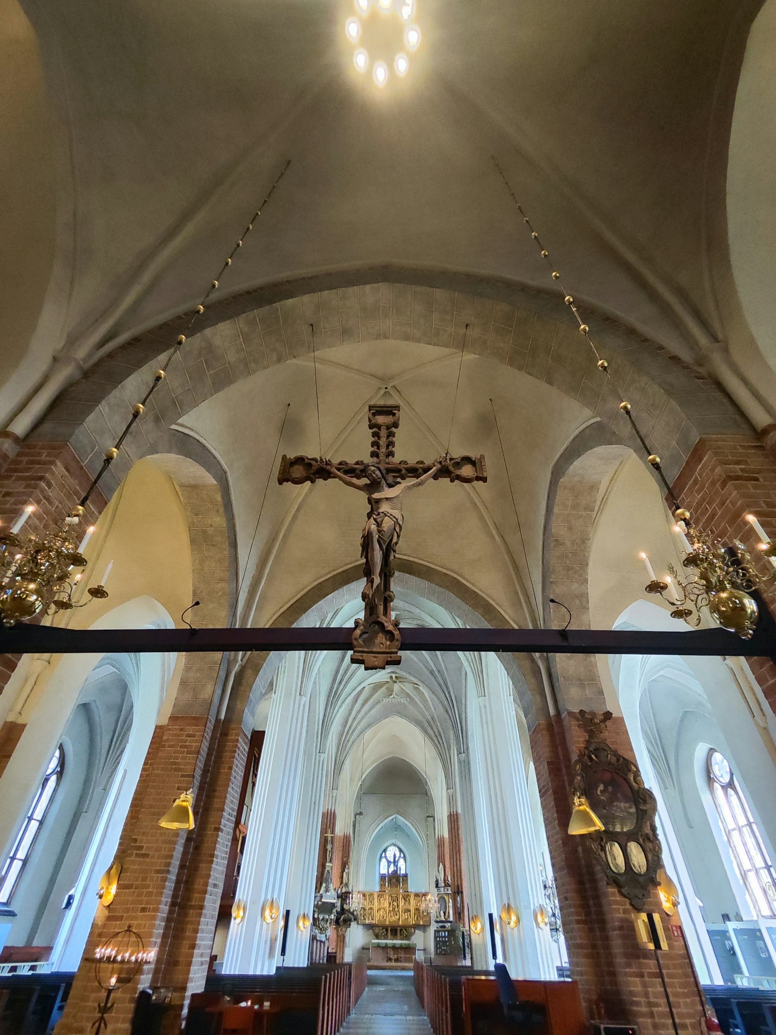 Vista interior de una iglesia con techos en arco y un crucifijo prominente