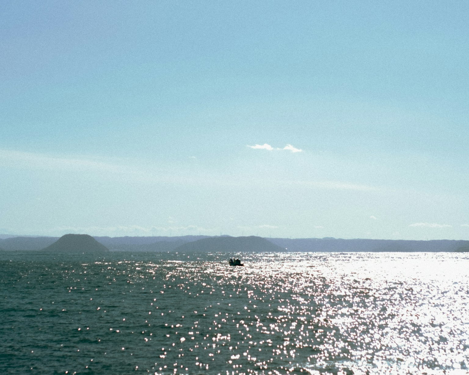 A small boat on sparkling blue water under a clear sky