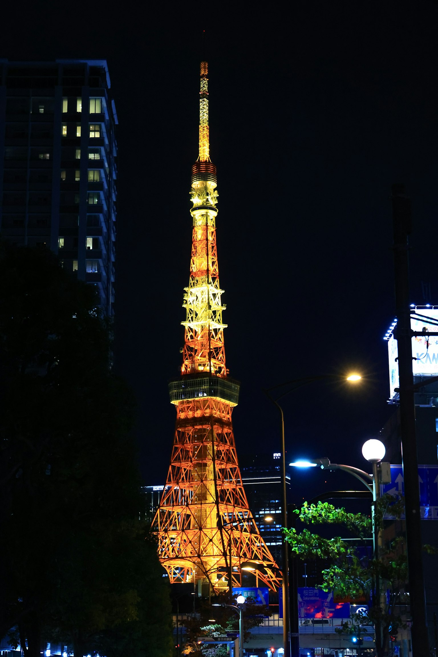 東京塔在夜間照亮，周圍有建築