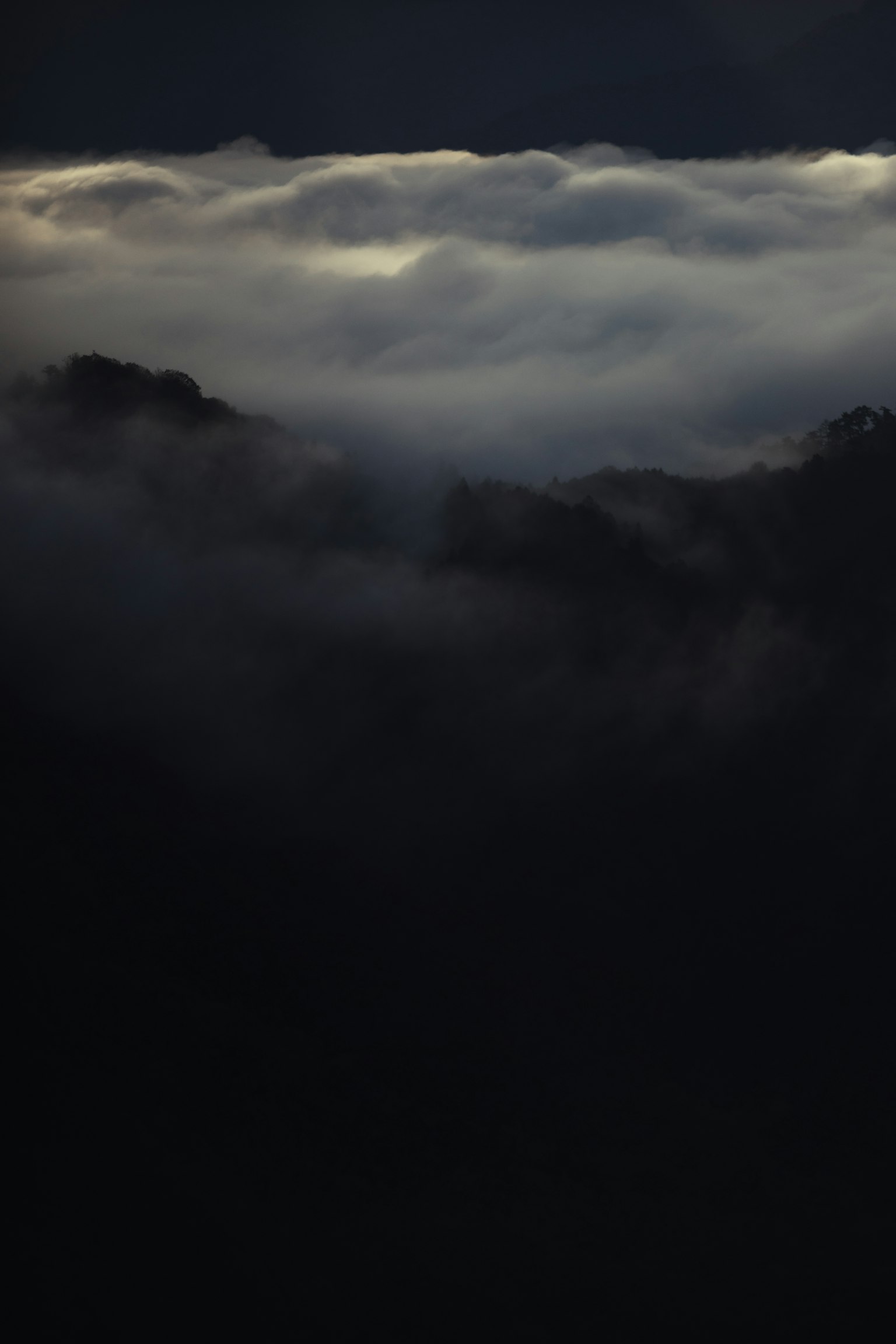 A landscape with dim light breaking through dark clouds