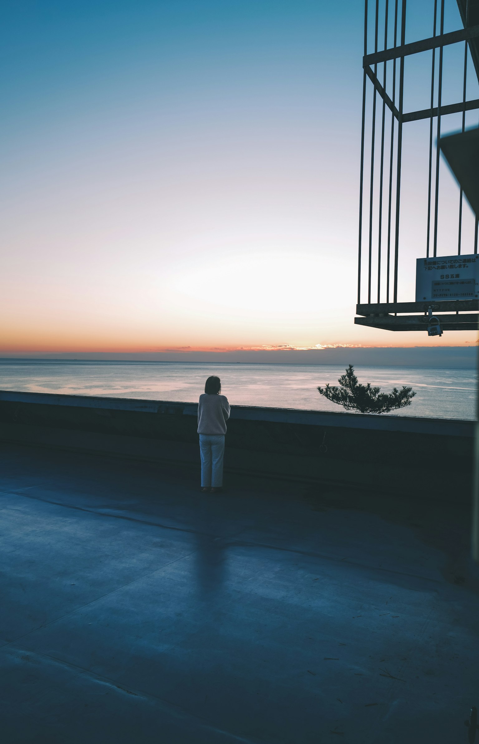 Une femme en blanc se tenant devant un magnifique coucher de soleil sur l'océan