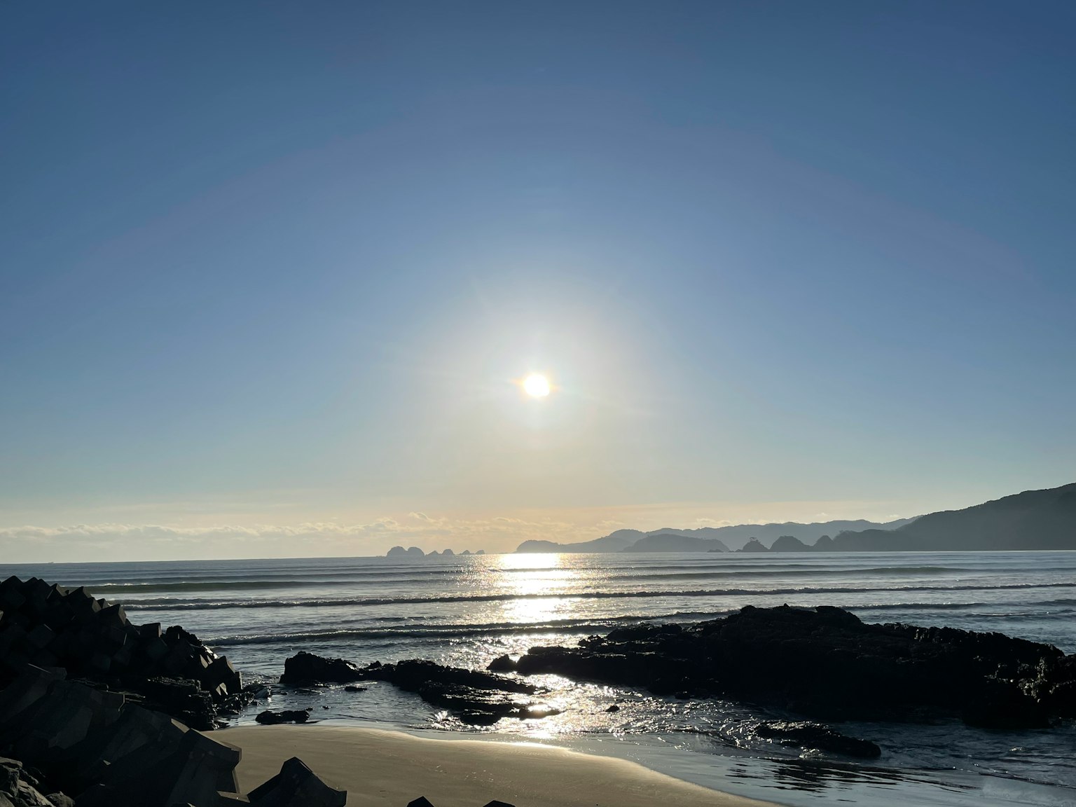 Vista serena della spiaggia con il tramonto che si riflette sull'acqua
