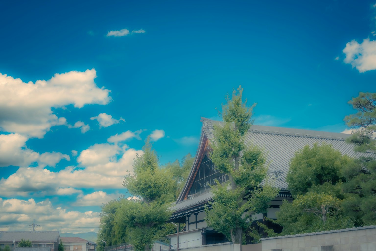 在藍天和白雲下部分可見的傳統建築和綠色樹木
