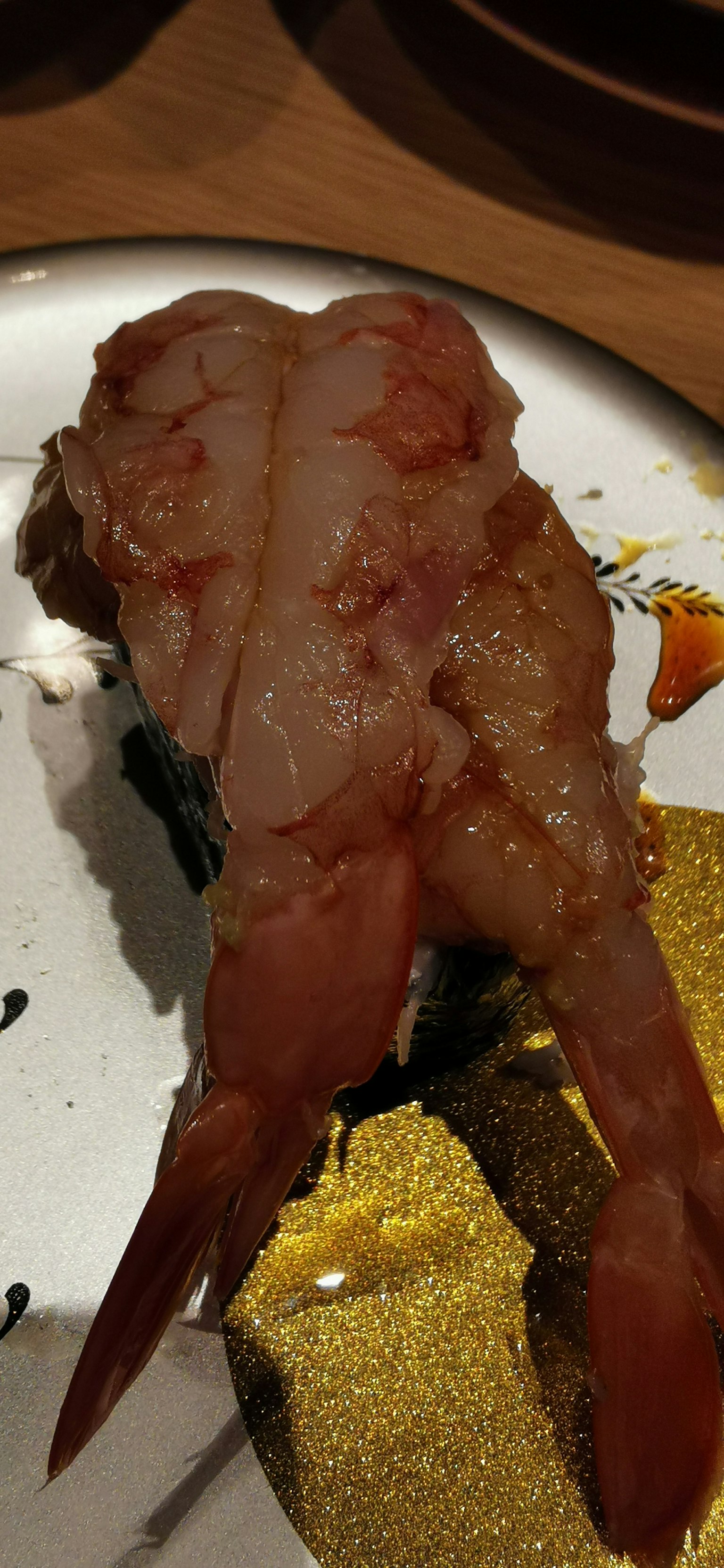 Hidangan ikan unik di atas piring dengan daging berwarna coklat kemerahan yang mengkilap