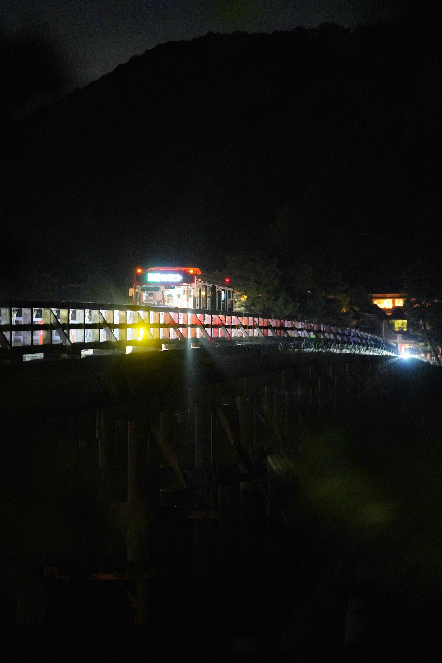 Night view of a bridge illuminated with lights and mountain silhouette