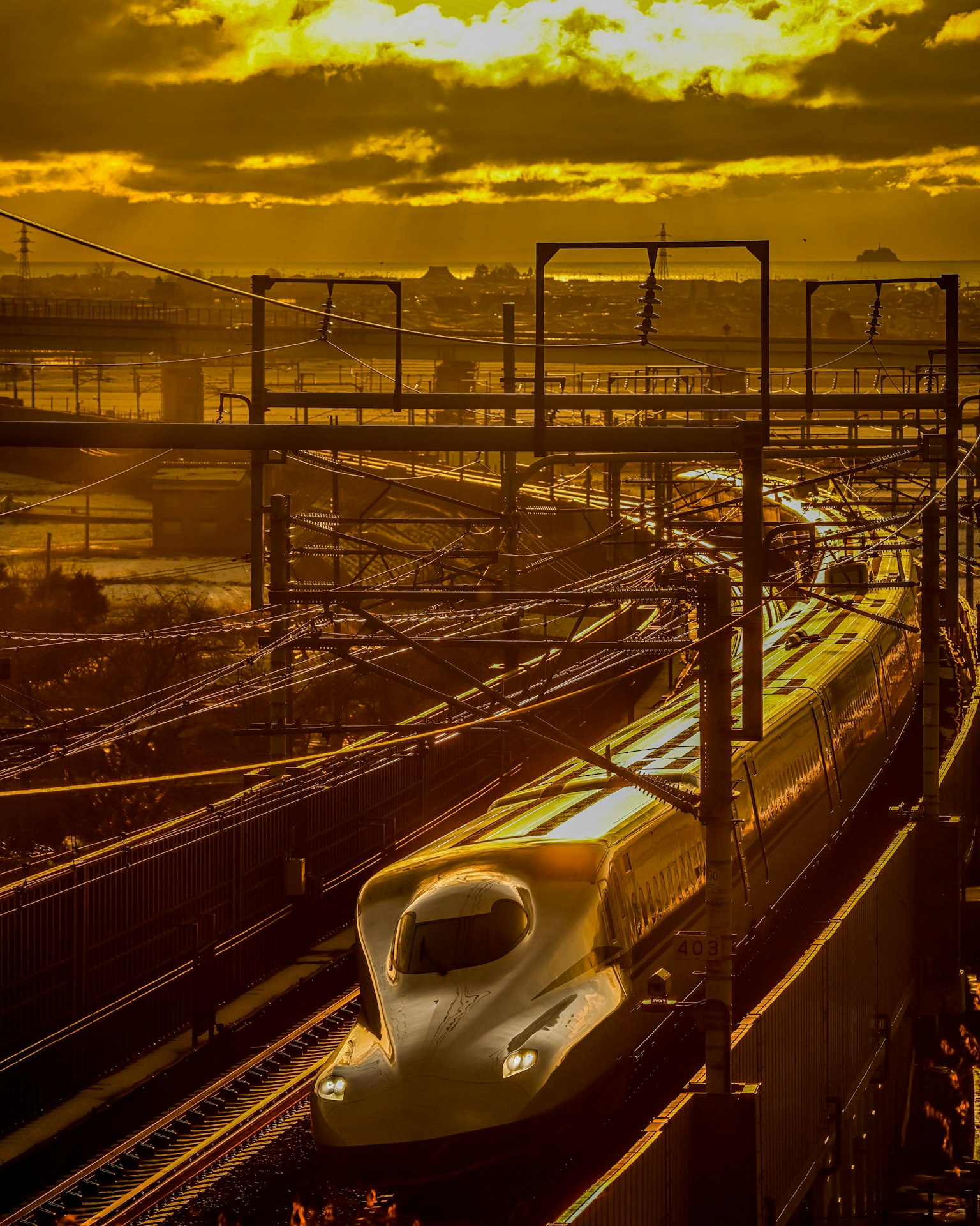 Tàu Shinkansen di chuyển qua hoàng hôn với dây điện