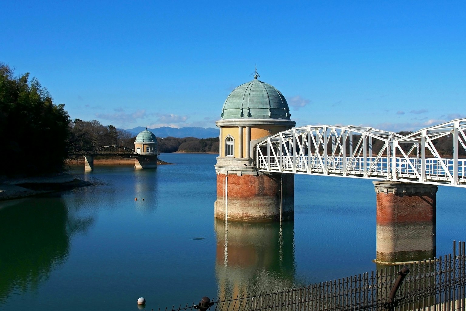 Pemandangan waduk dan jembatan putih di bawah langit biru