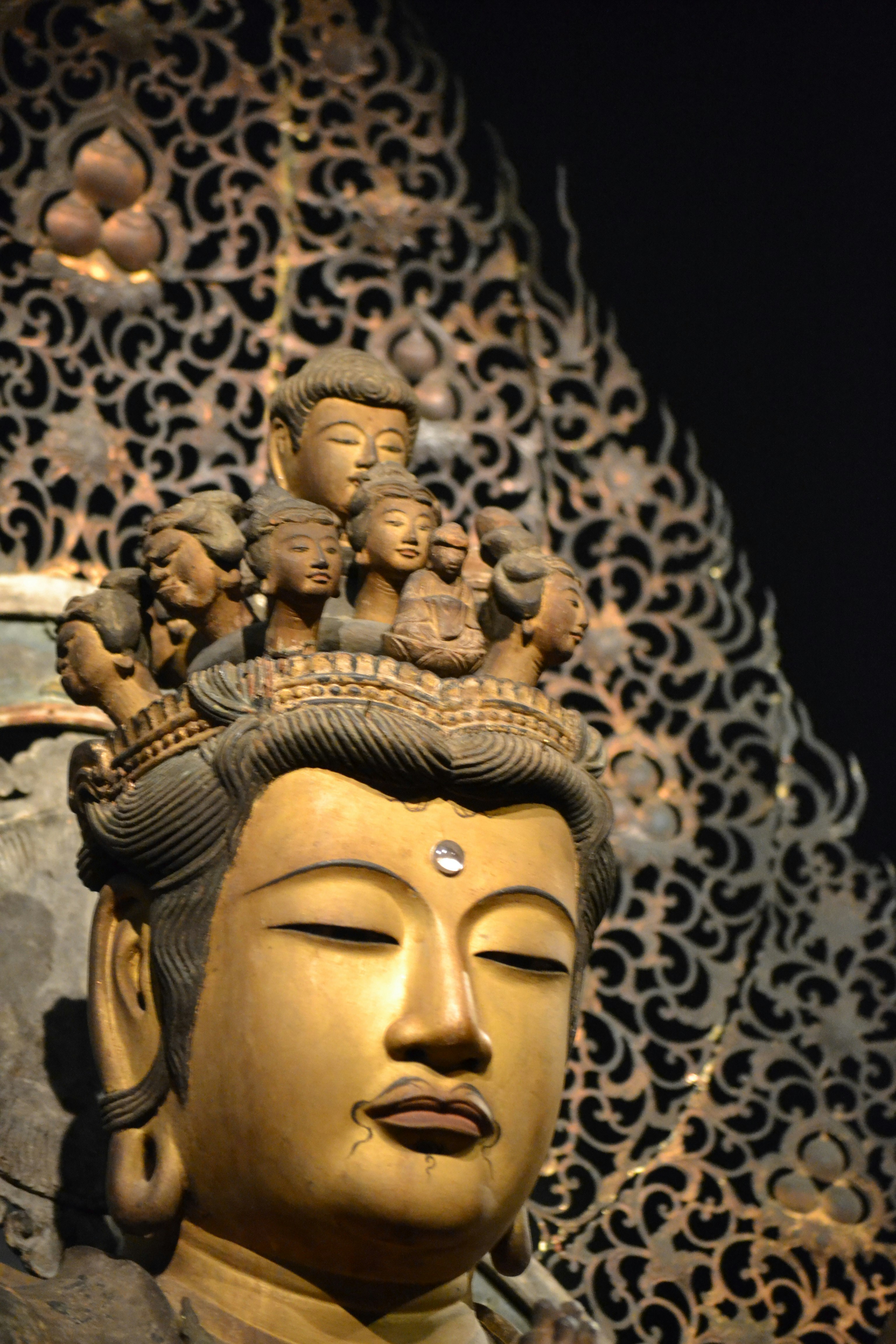 Nahaufnahme des Gesichts einer Buddha-Statue vor verziertem Musterhintergrund