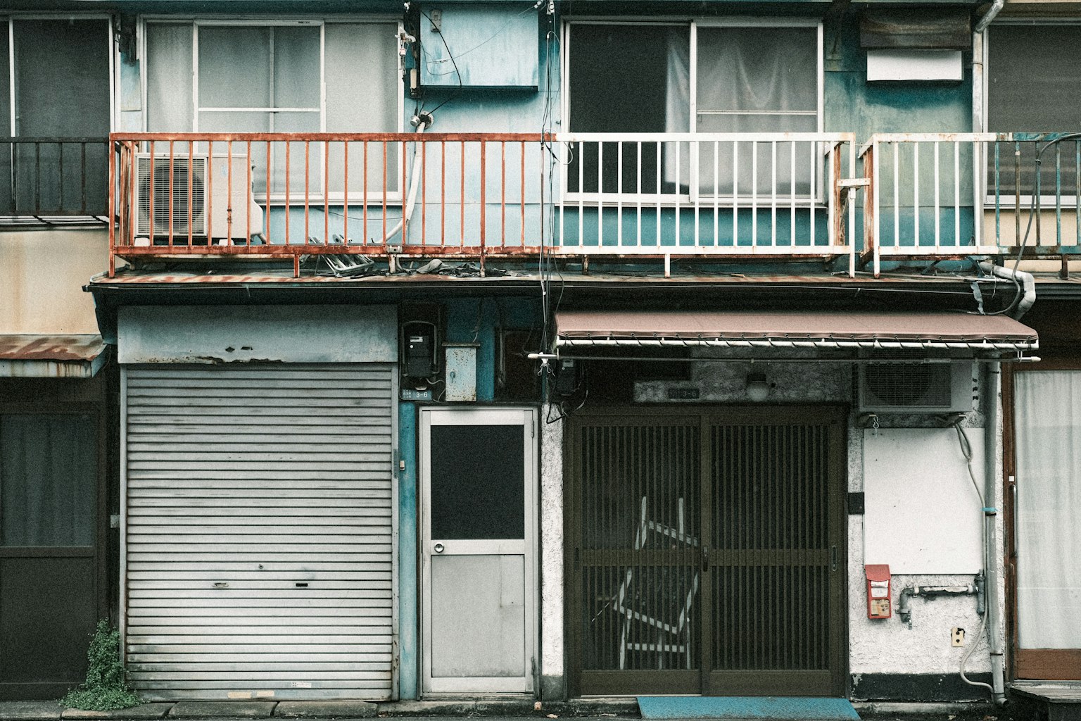 Exterior of an old apartment building with closed shutters and visible balcony