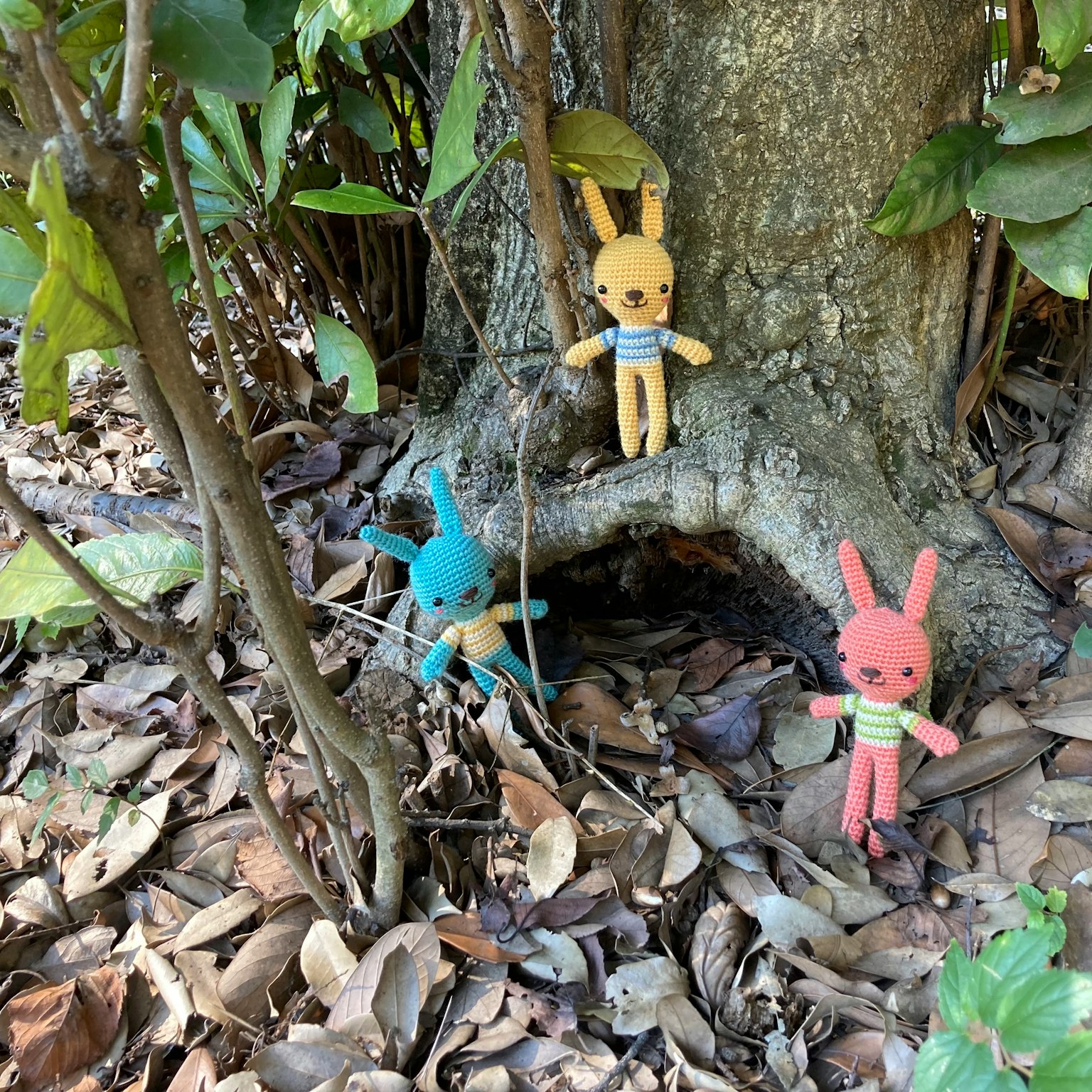Giocattoli di peluche colorati a forma di coniglio alla base di un albero