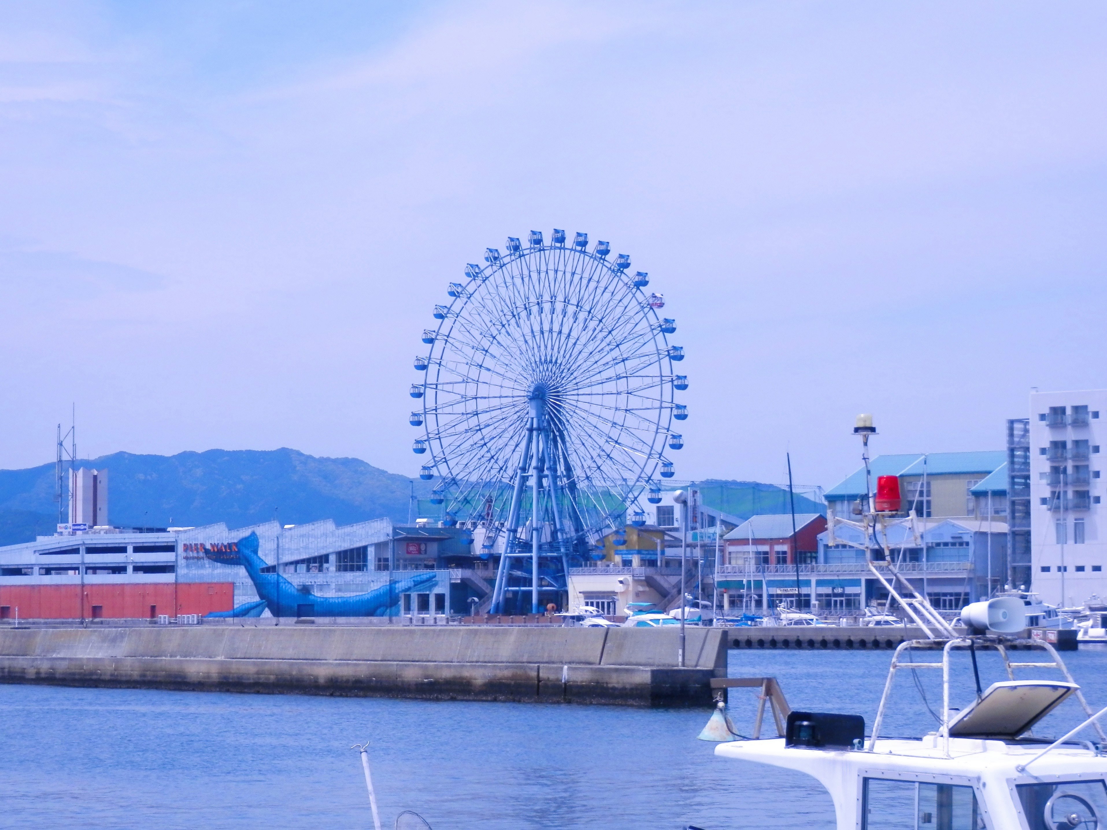 vista del porto sul mare con un battello turistico e una ruota panoramica