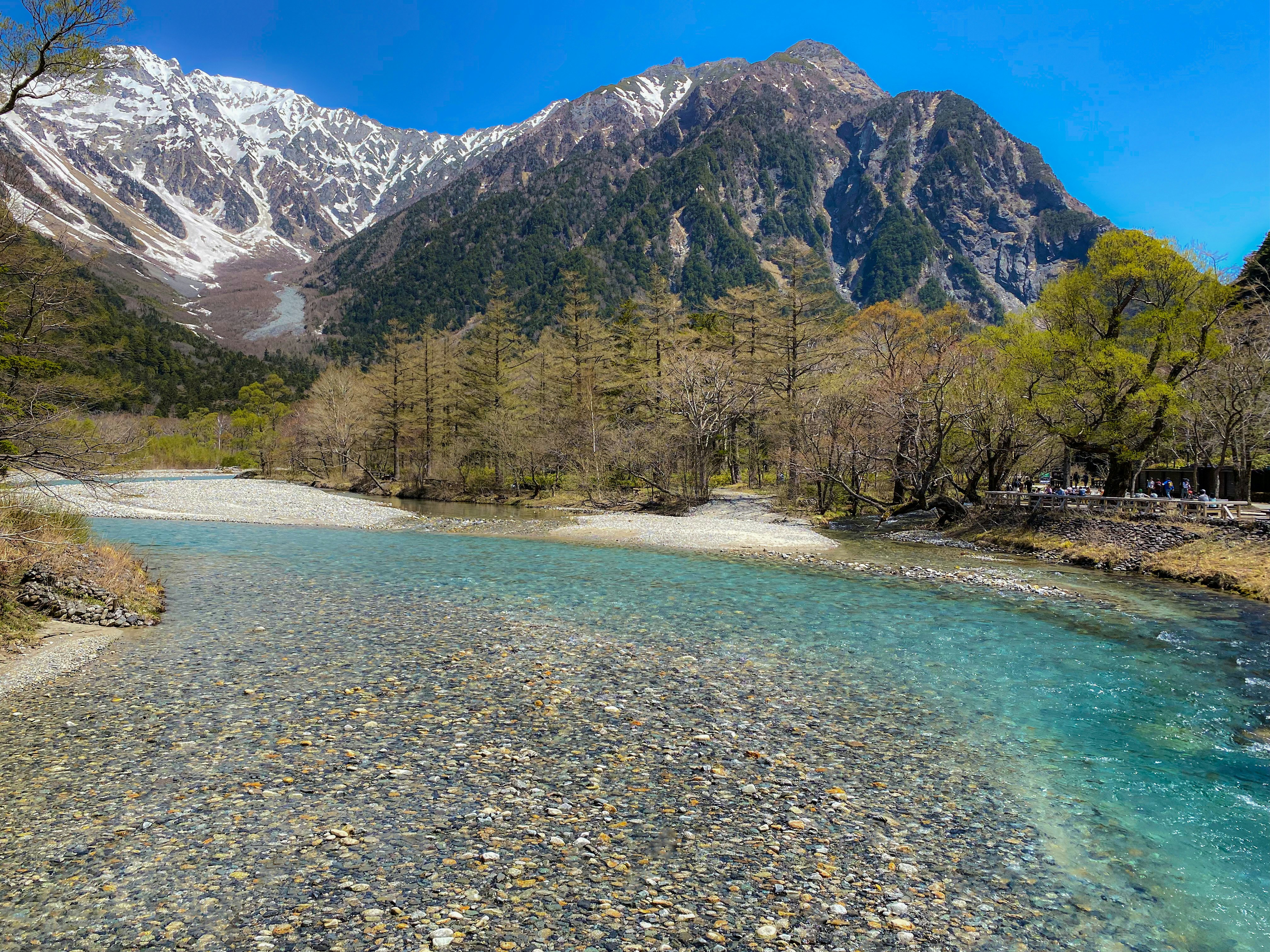 Kamikochi clear river with snow-capped mountains under a blue sky