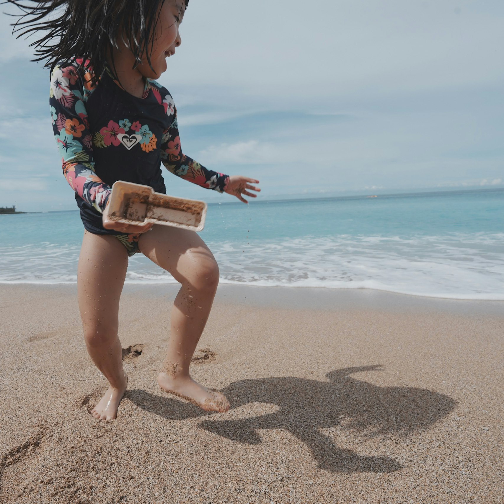 砂浜で貝殻を手にする子どもの遊ぶ姿