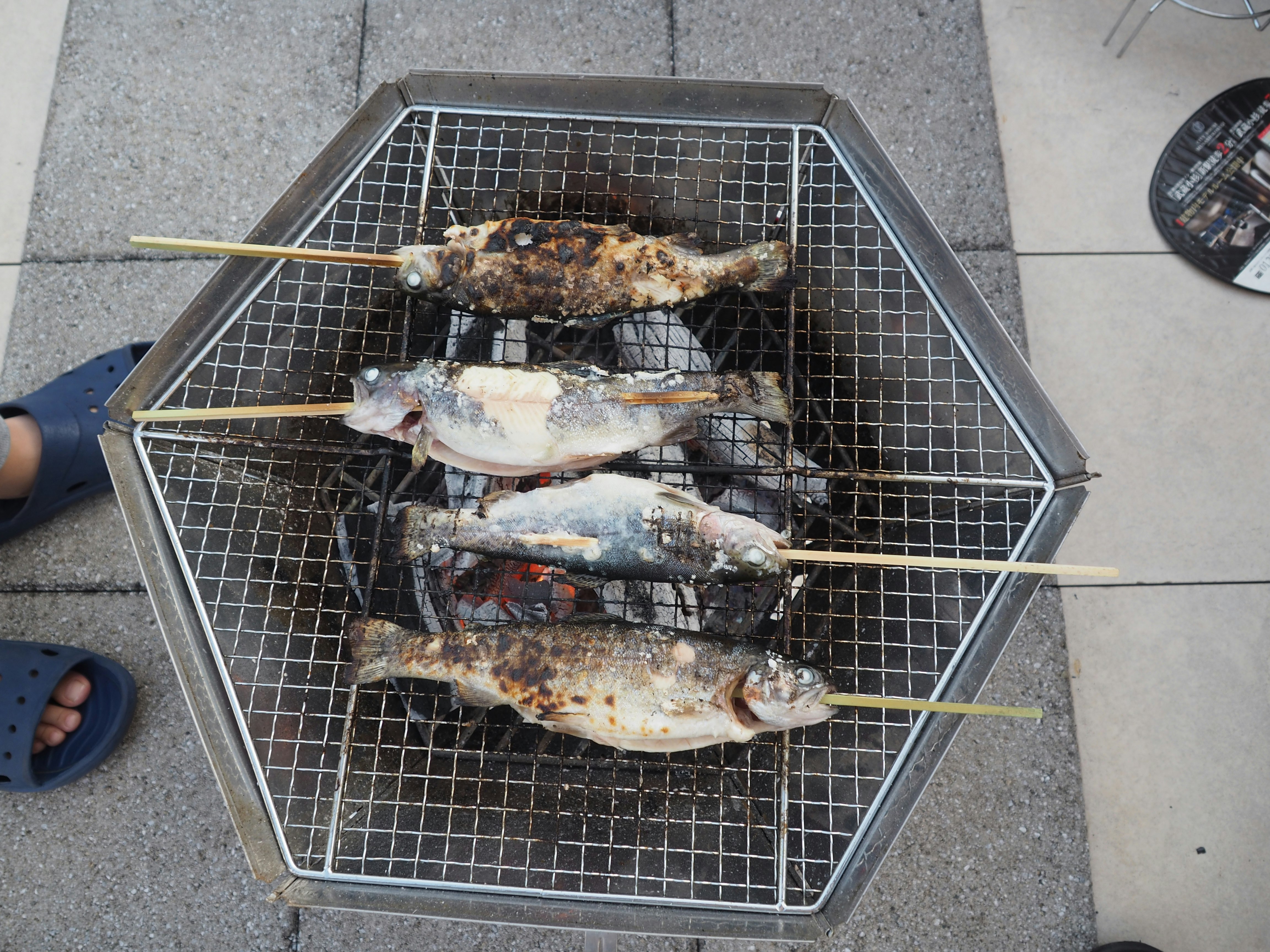 網の上で焼かれる鮎と焼き魚のバーベキュー