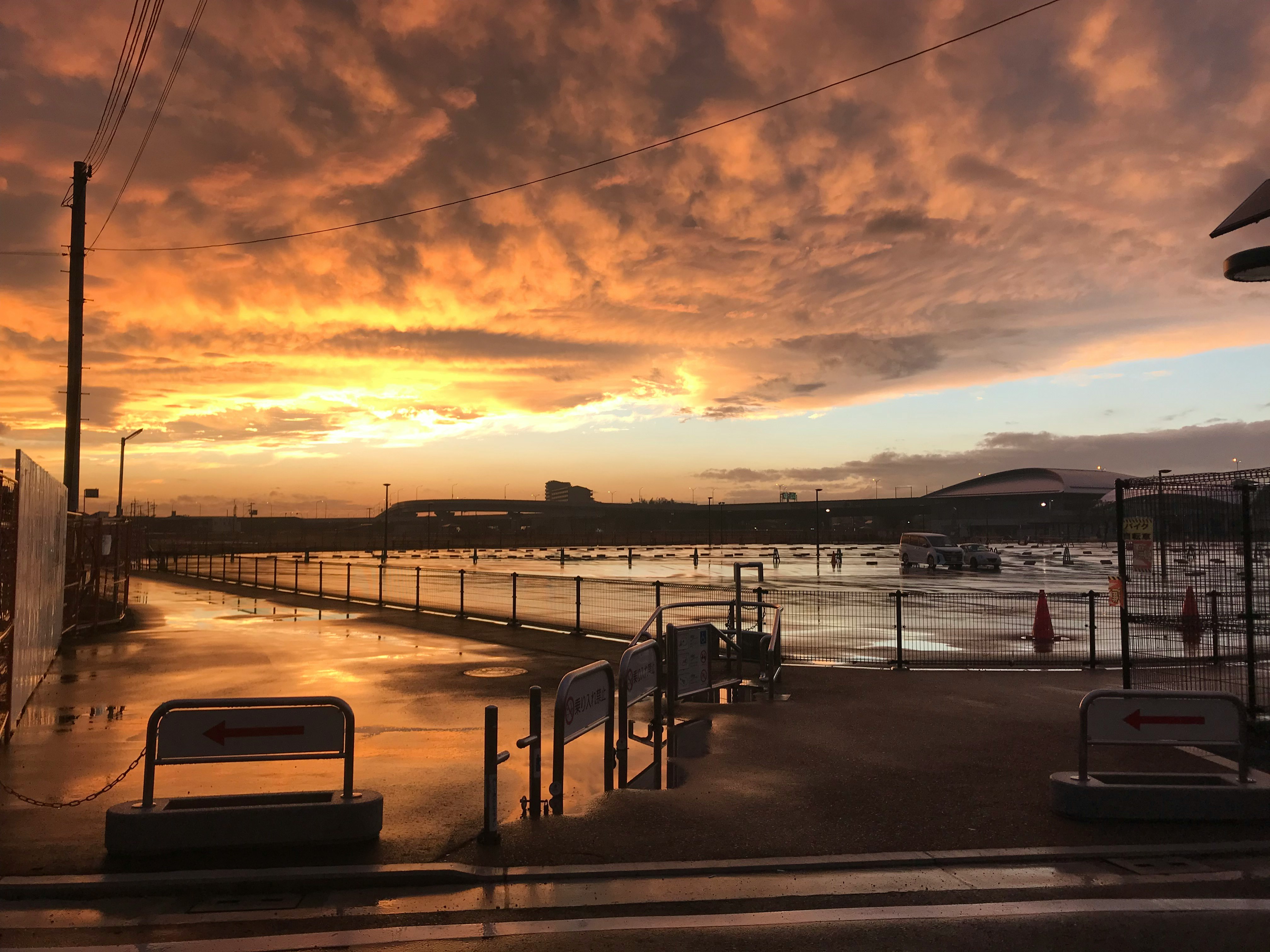 夕暮れの海沿いの駐車場とフェンスのある岸壁
