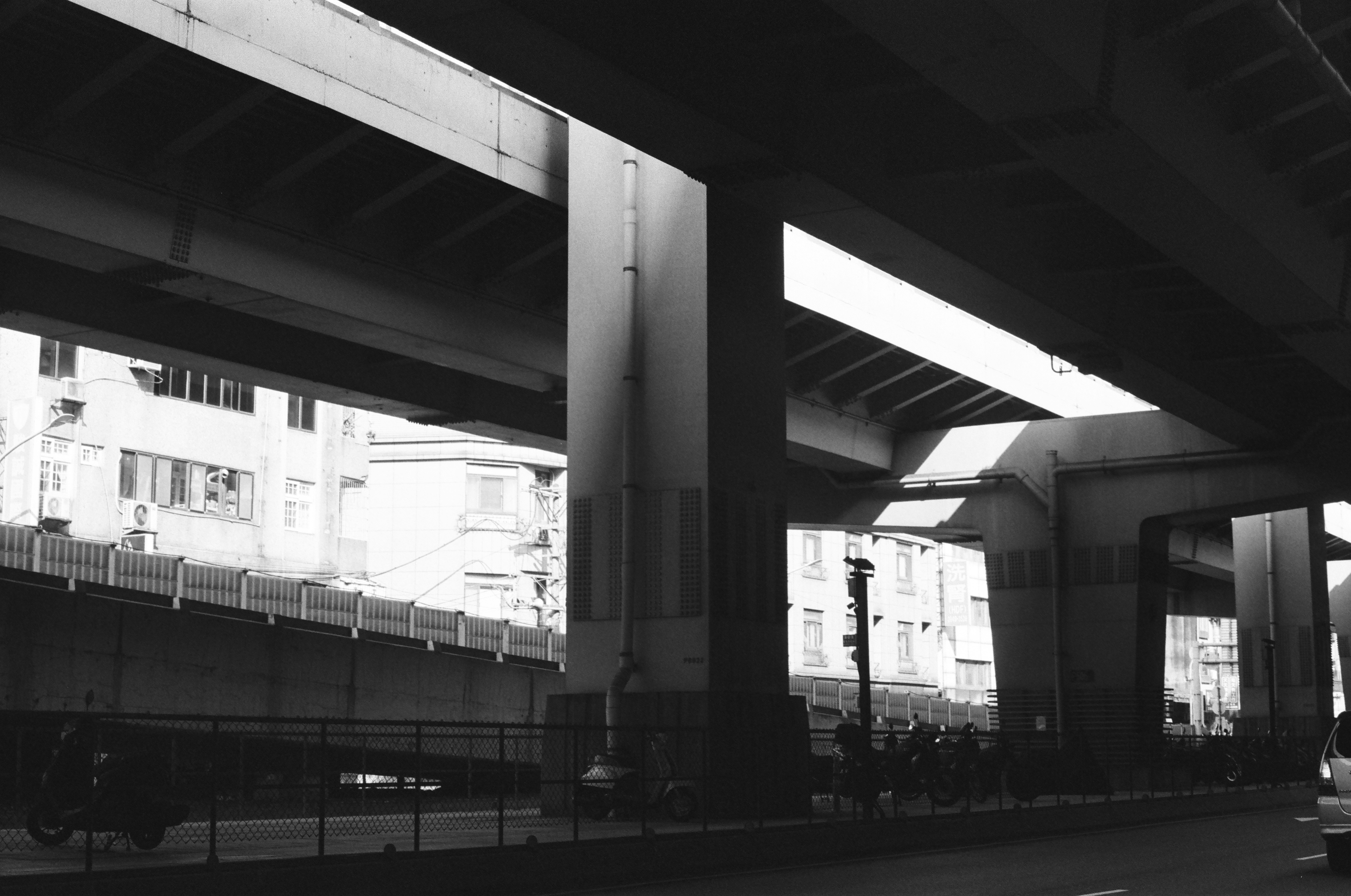 高架下の柱と通路が続くモノクロの都市風景