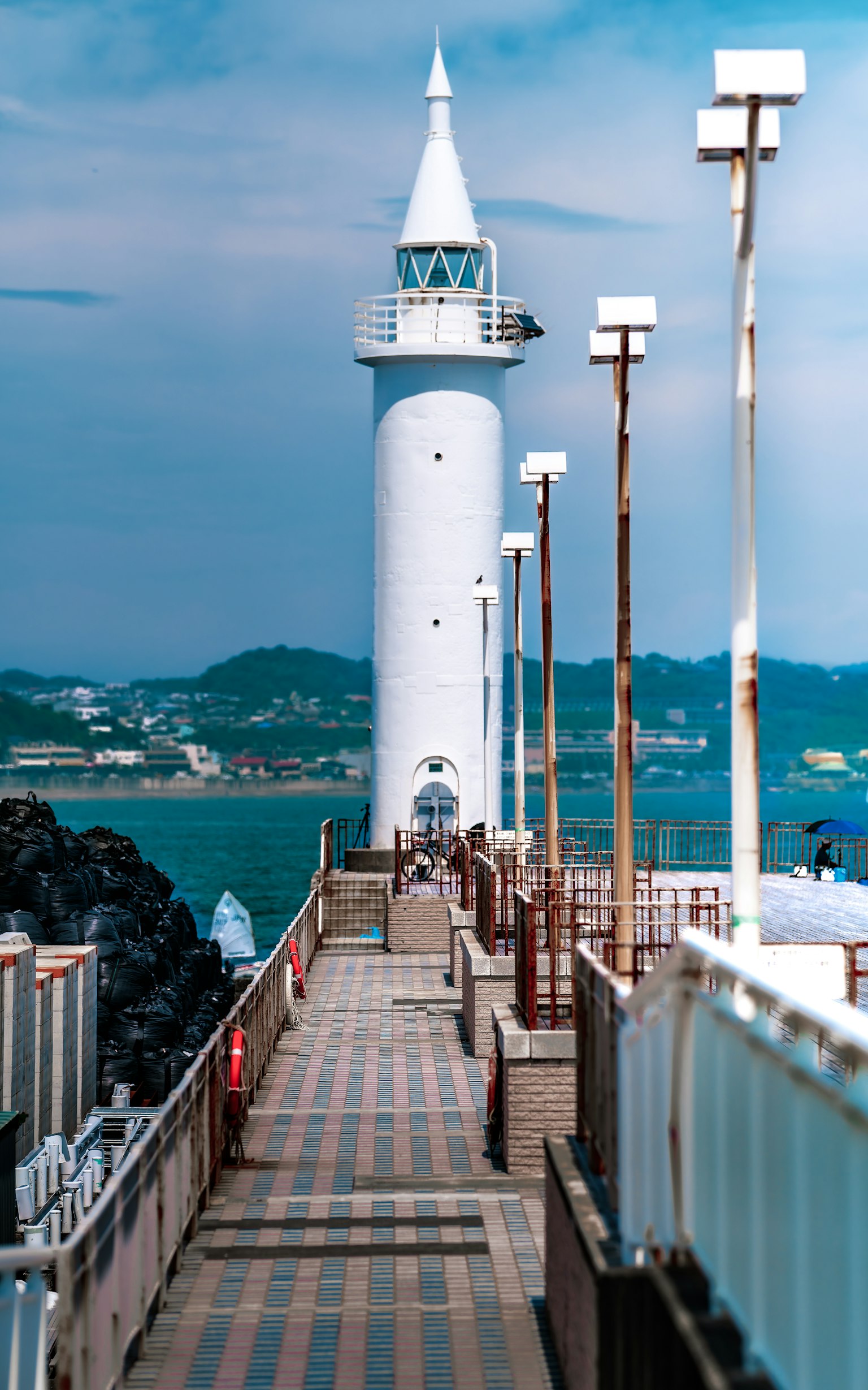Un faro bianco su un molo con l'oceano blu sullo sfondo