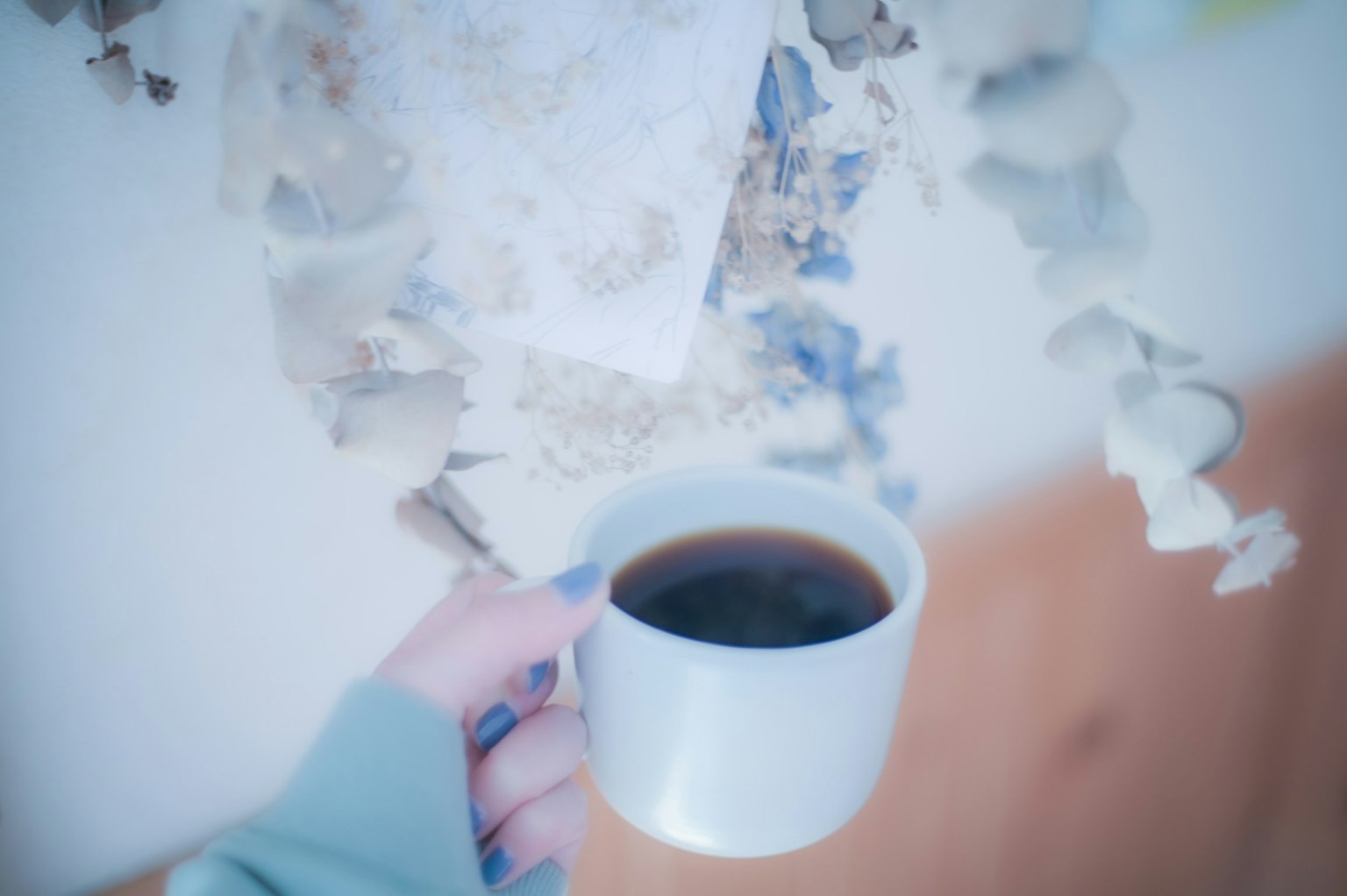 Bild einer Hand, die eine weiße Kaffeetasse hält