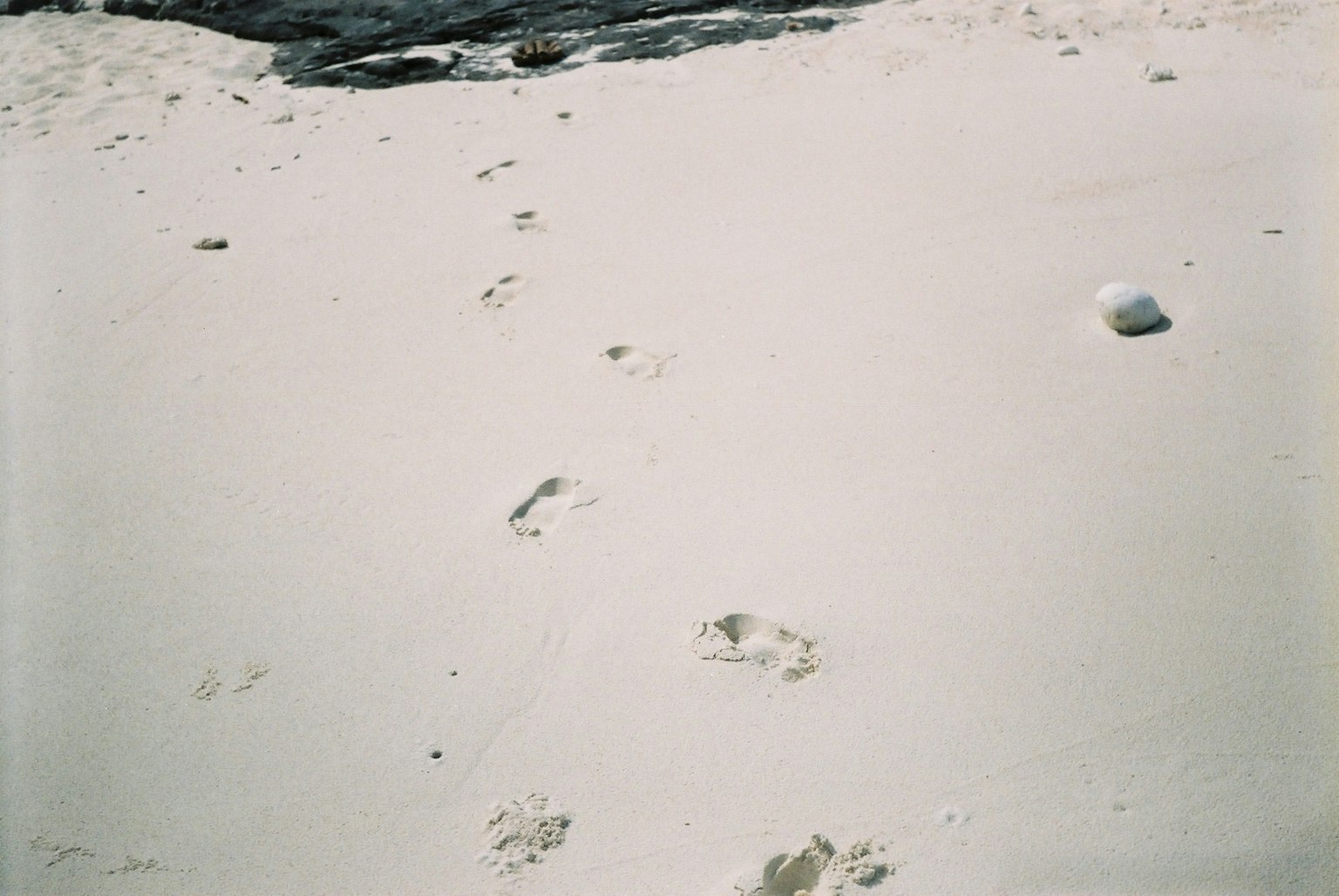 Empreintes sur une plage de sable blanc avec des rochers