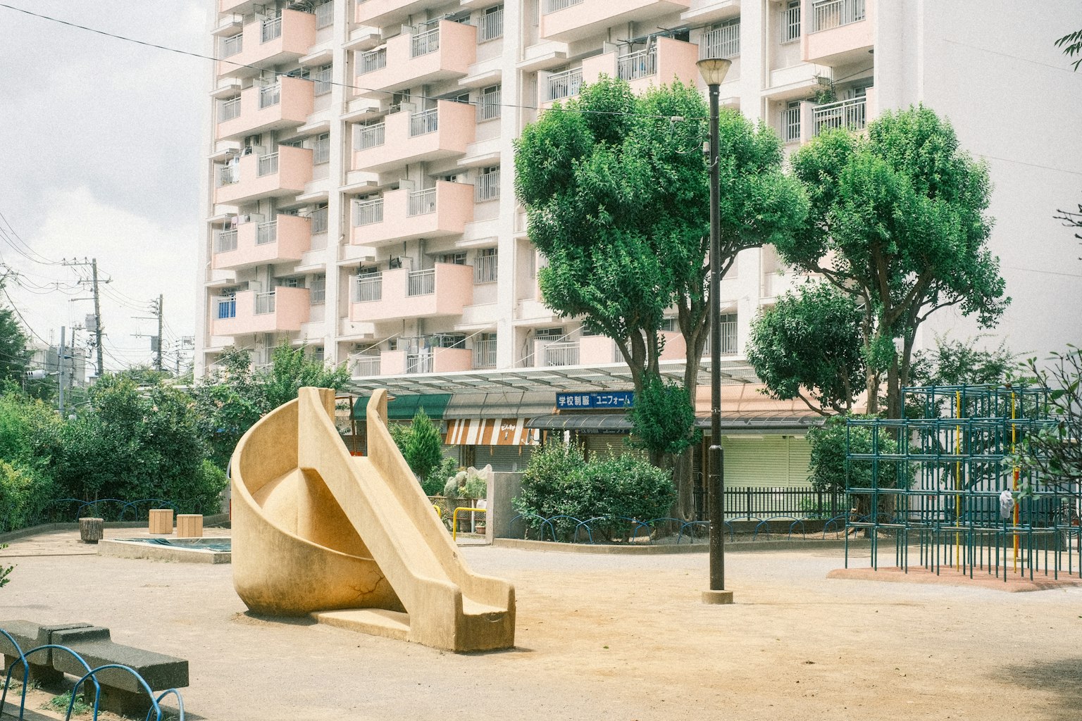 Playground slide with surrounding trees and an apartment building