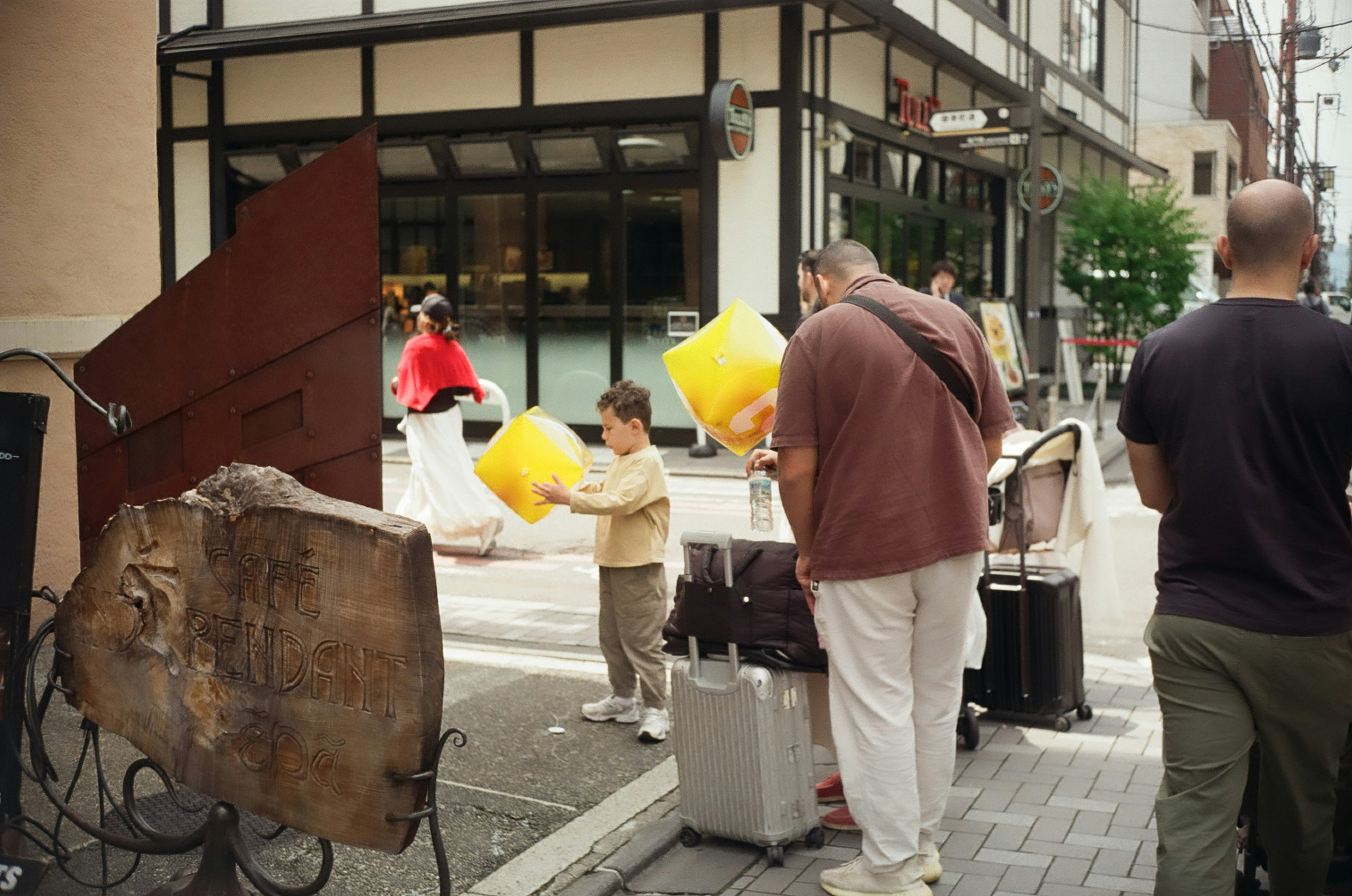 路地の店先で黄色い袋を持つ人と買い物客の行き交い