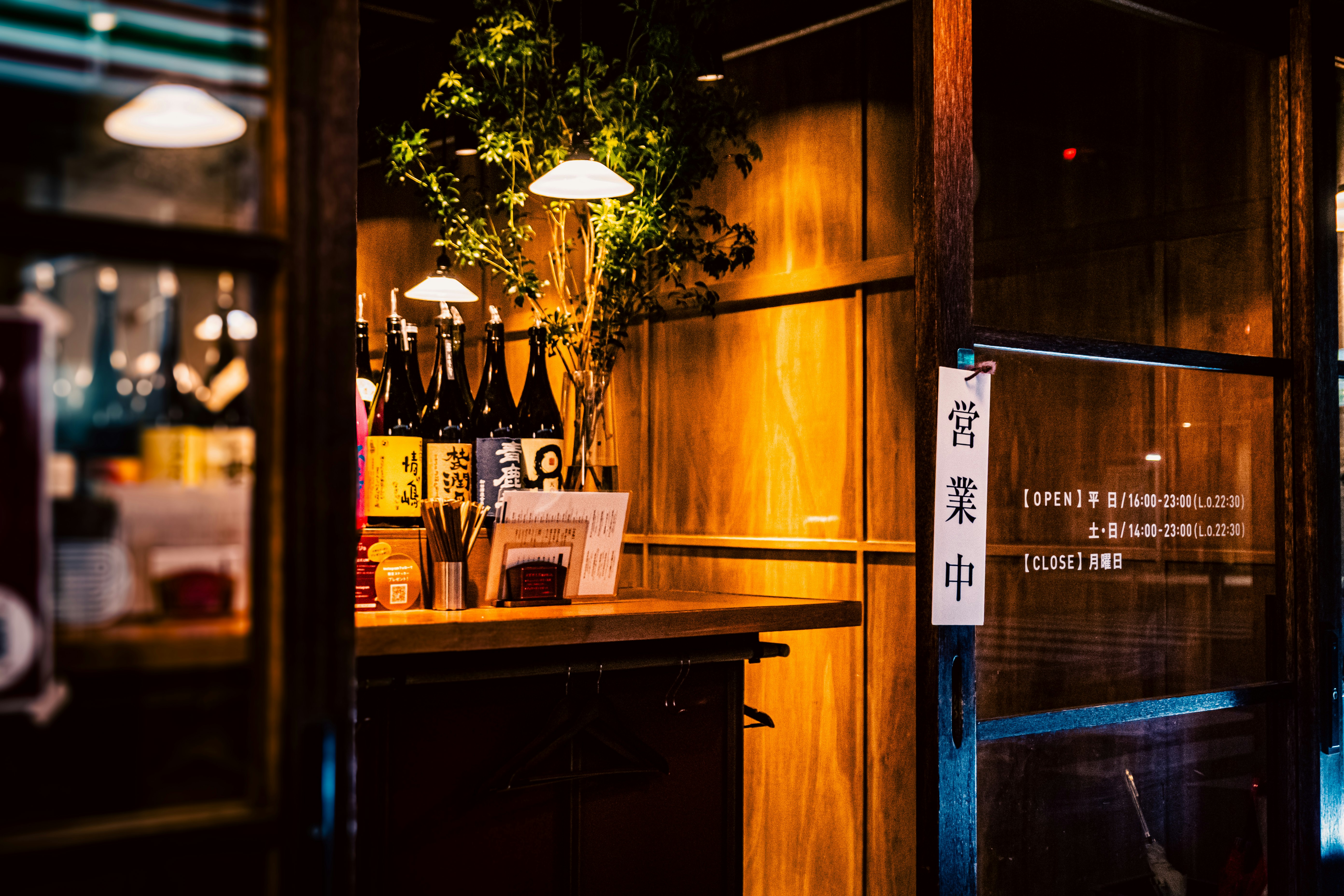 木の外壁に掲示された営業時間案内のある小さな店先
