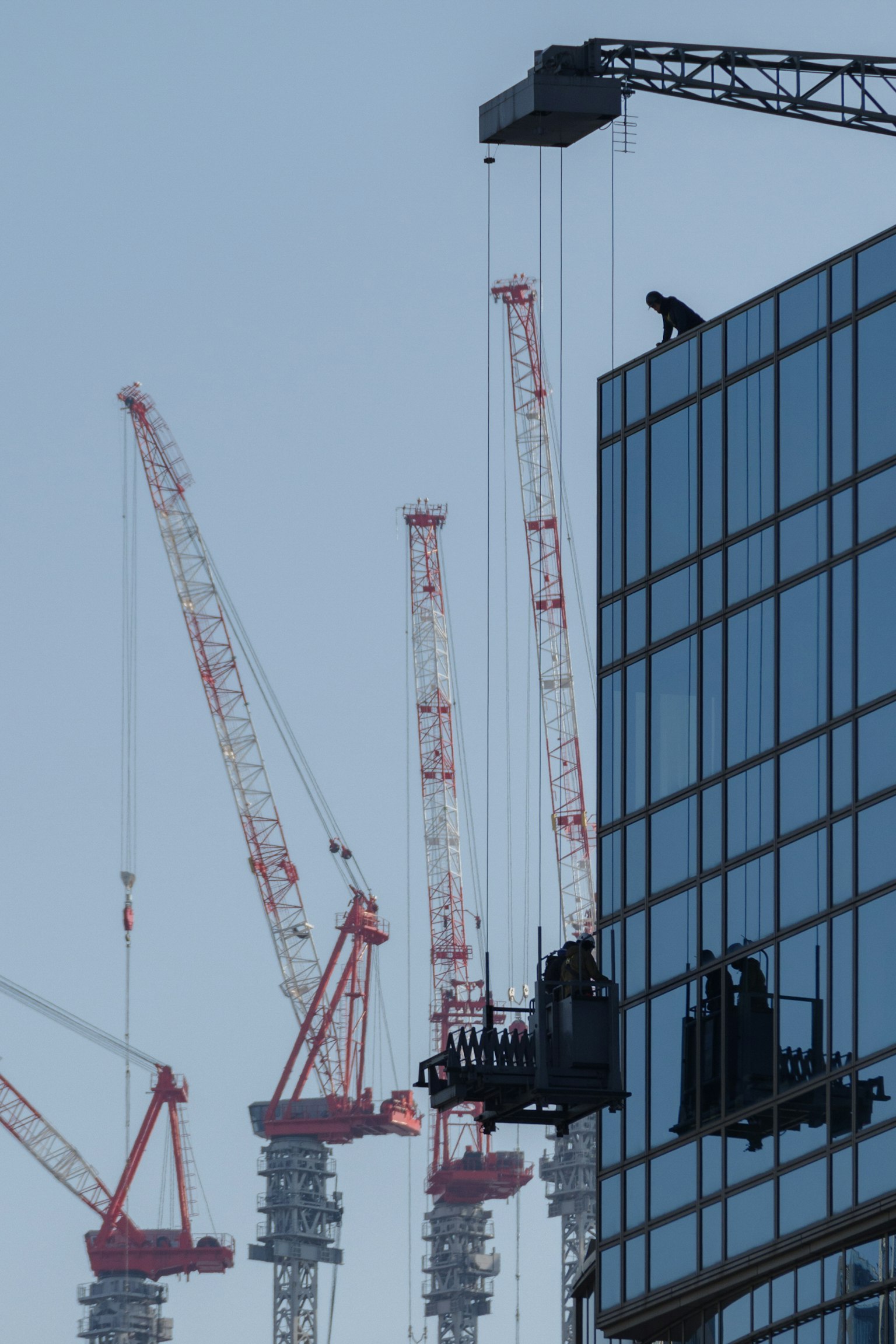 高層建築外牆上的工人，背景是高聳的起重機
