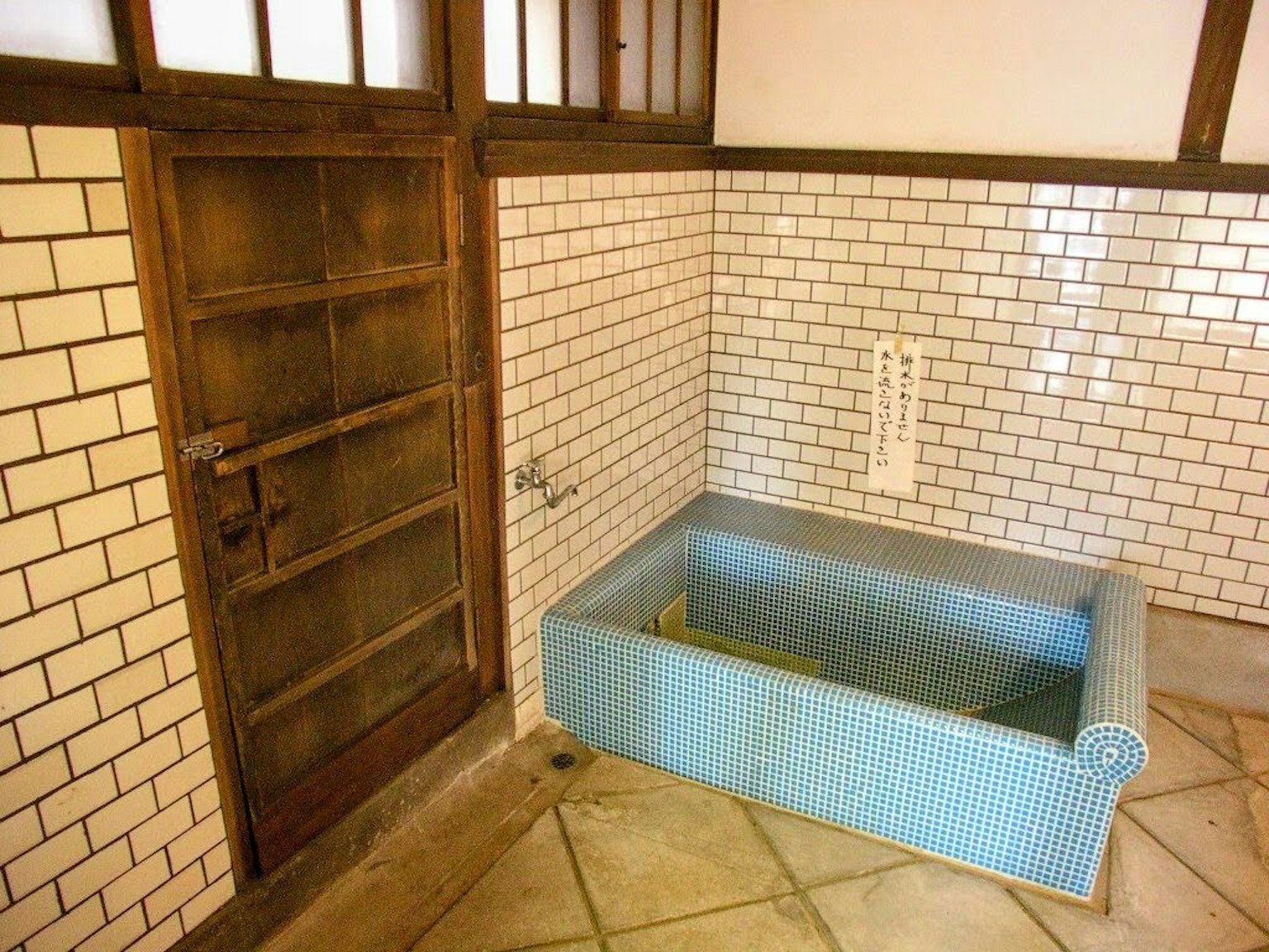 Intérieur d'une pièce traditionnelle avec une baignoire bleue sol carrelé et murs en briques