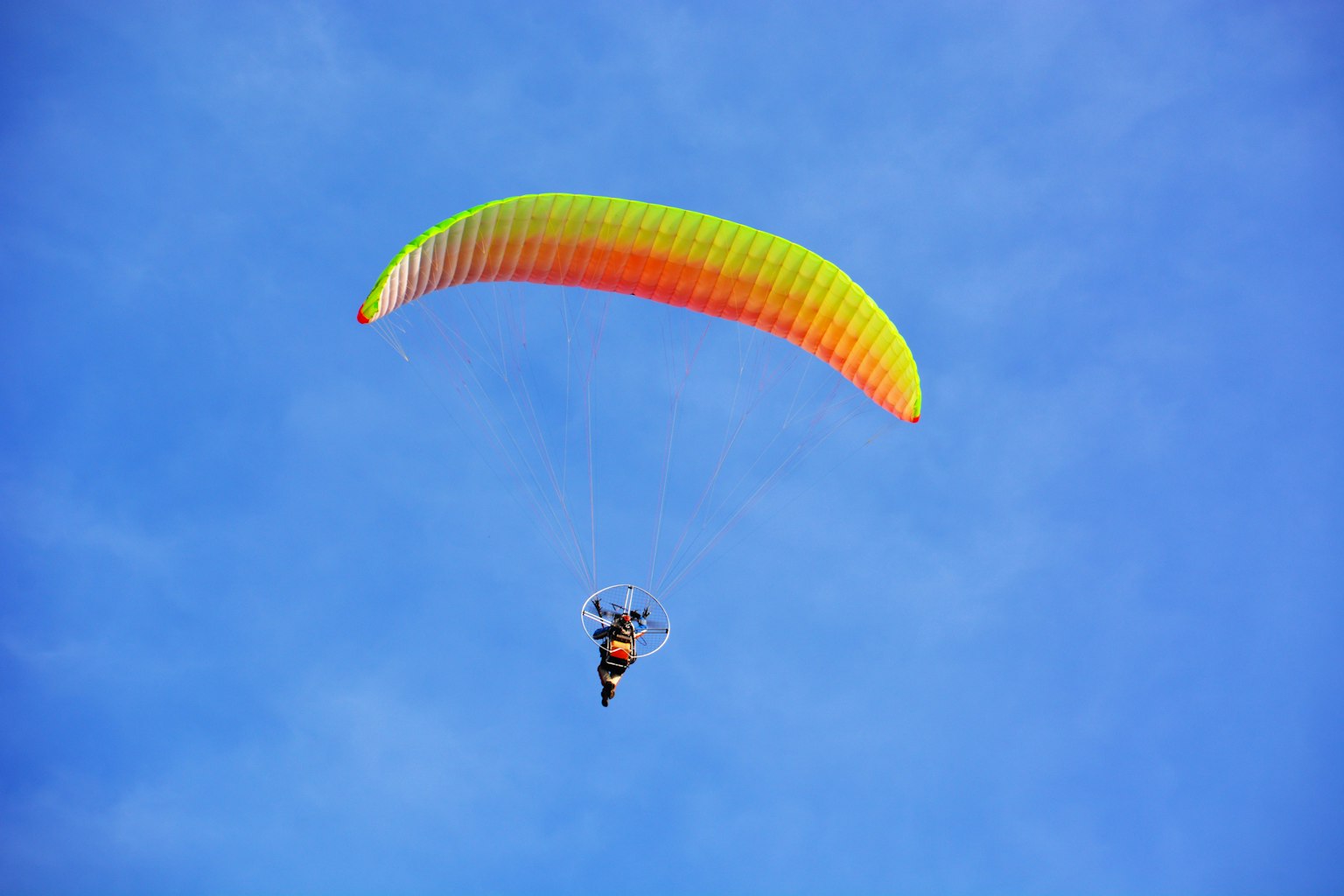 Un parapendio che vola in un cielo blu con un'ala colorata