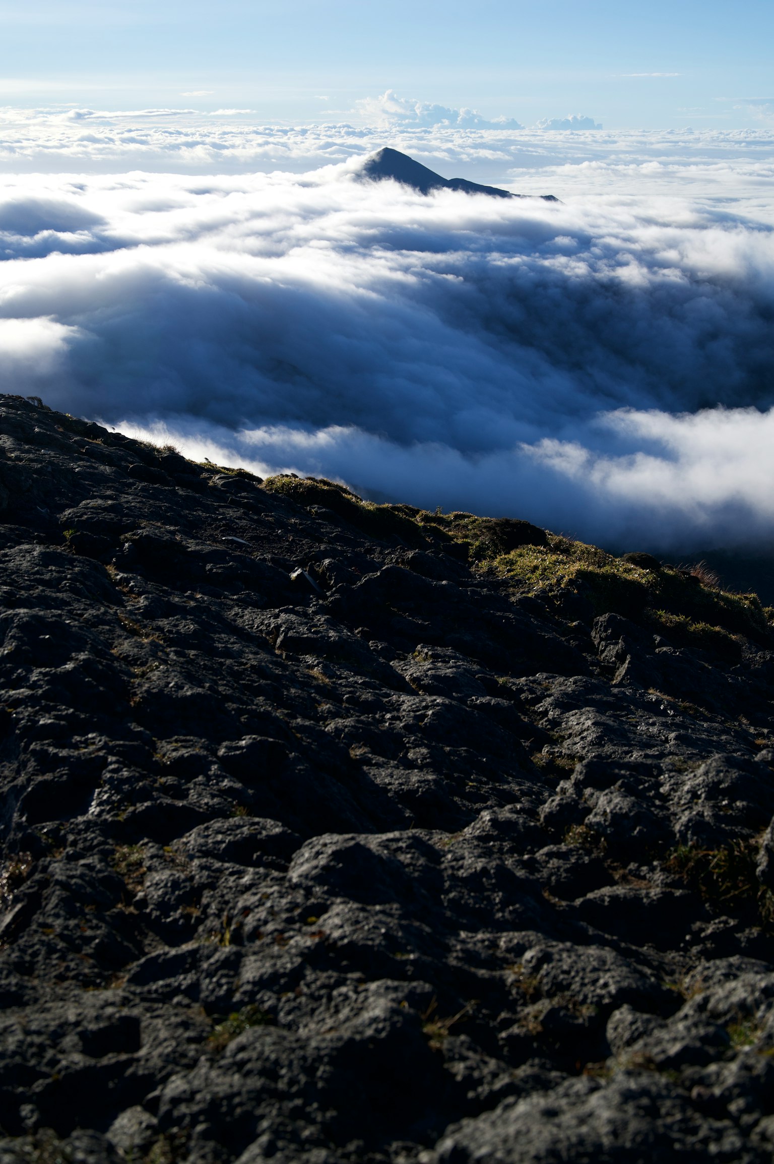 Vista dalla cima di una montagna che sovrasta un mare di nuvole con texture rocciose evidenti