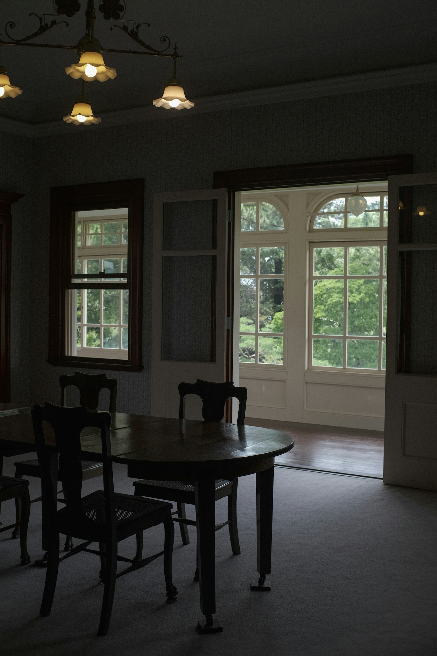 Intérieur d'une pièce lumineuse avec de grandes fenêtres présentant une table et des chaises