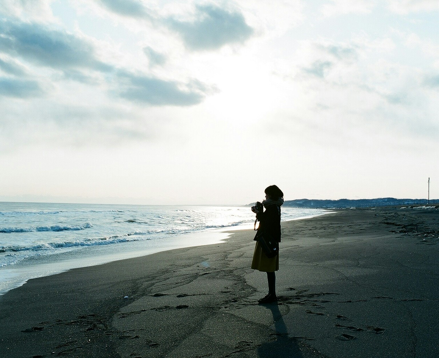 Silhouette of a child holding a camera on the beach