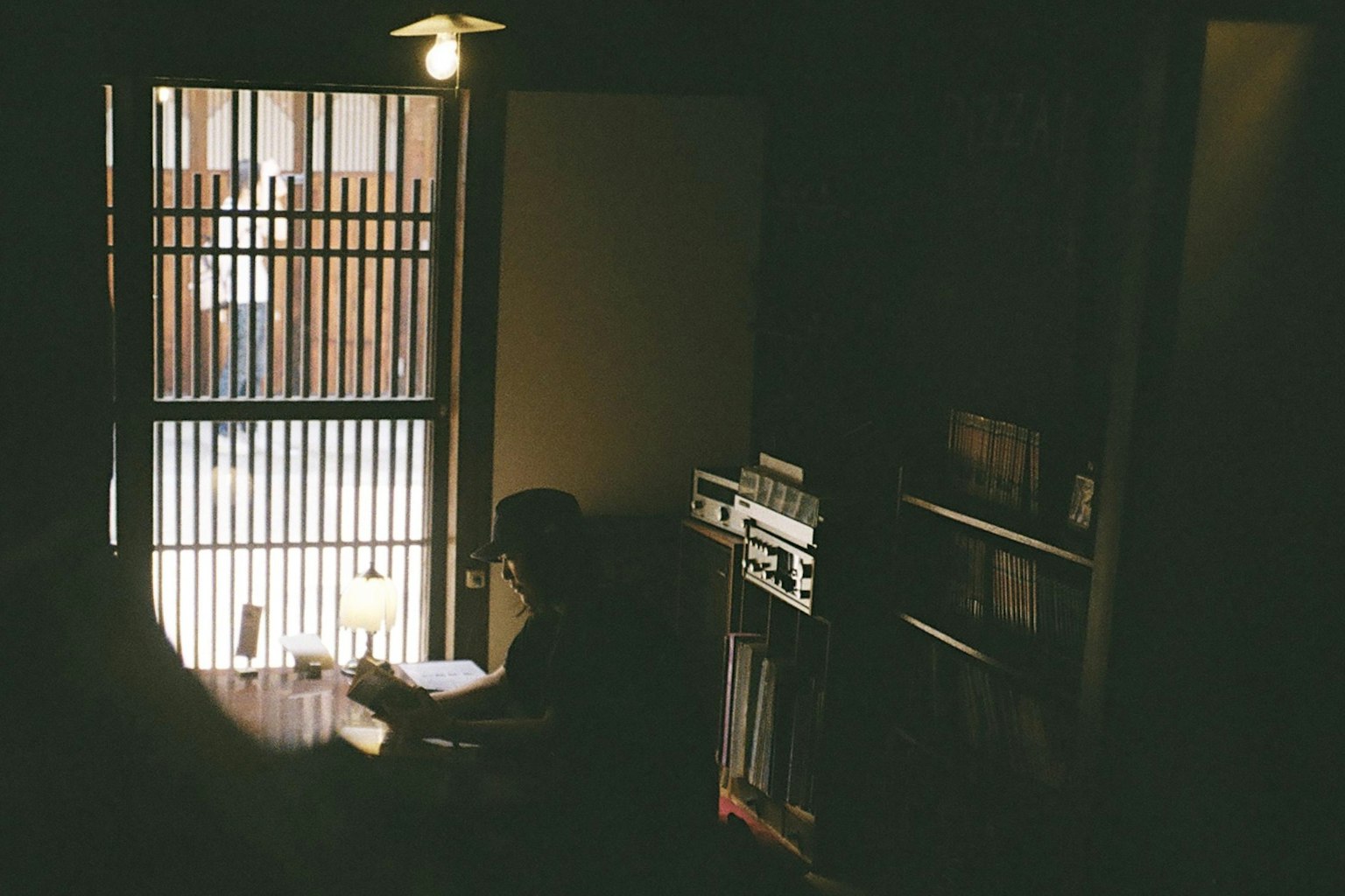 Silhouette einer Person, die in einem schwach beleuchteten Raum ein Buch liest Sanftes Licht strömt durch das Fenster