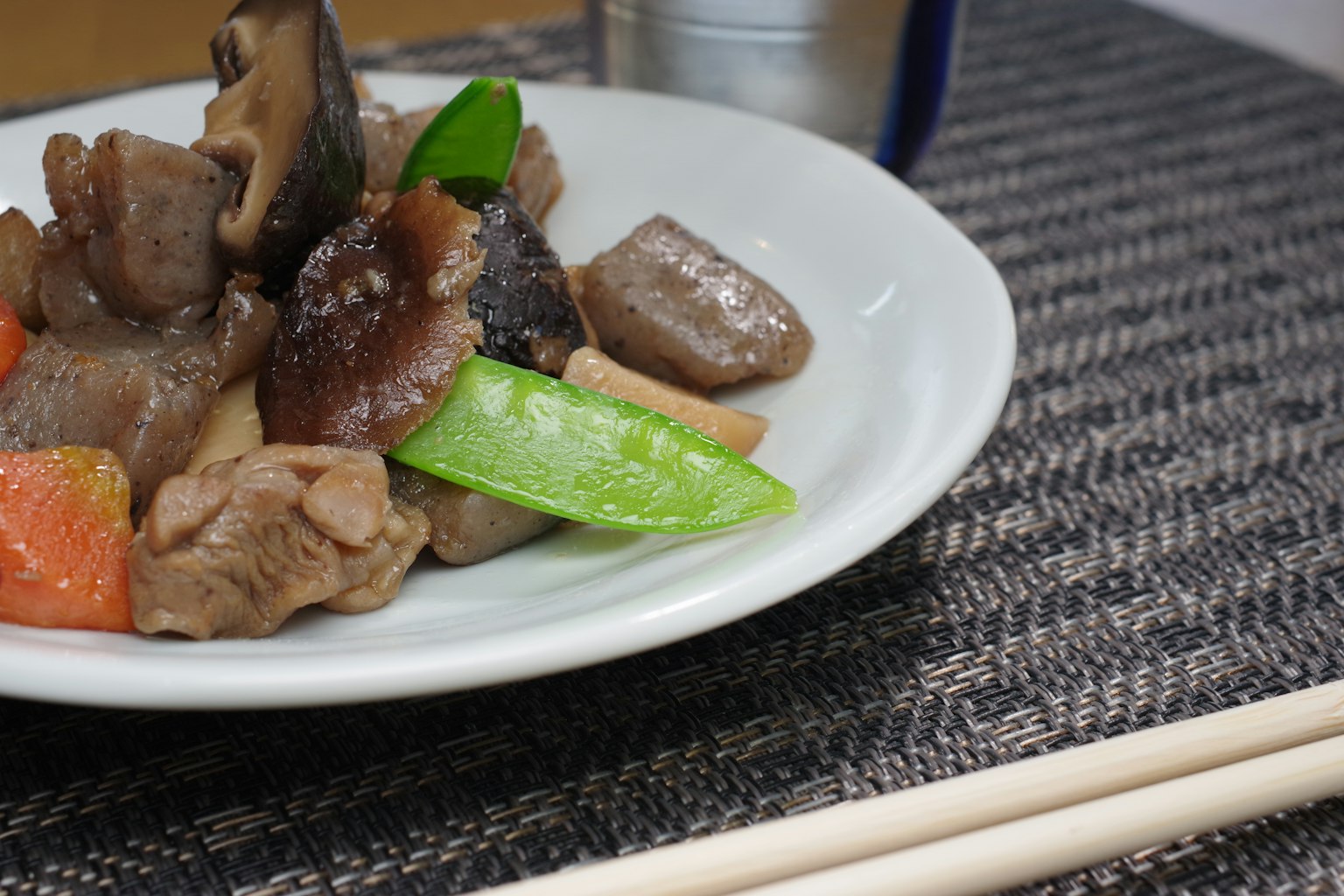Hidangan daging dan sayuran tumis di piring dengan jamur shiitake dan kacang polong