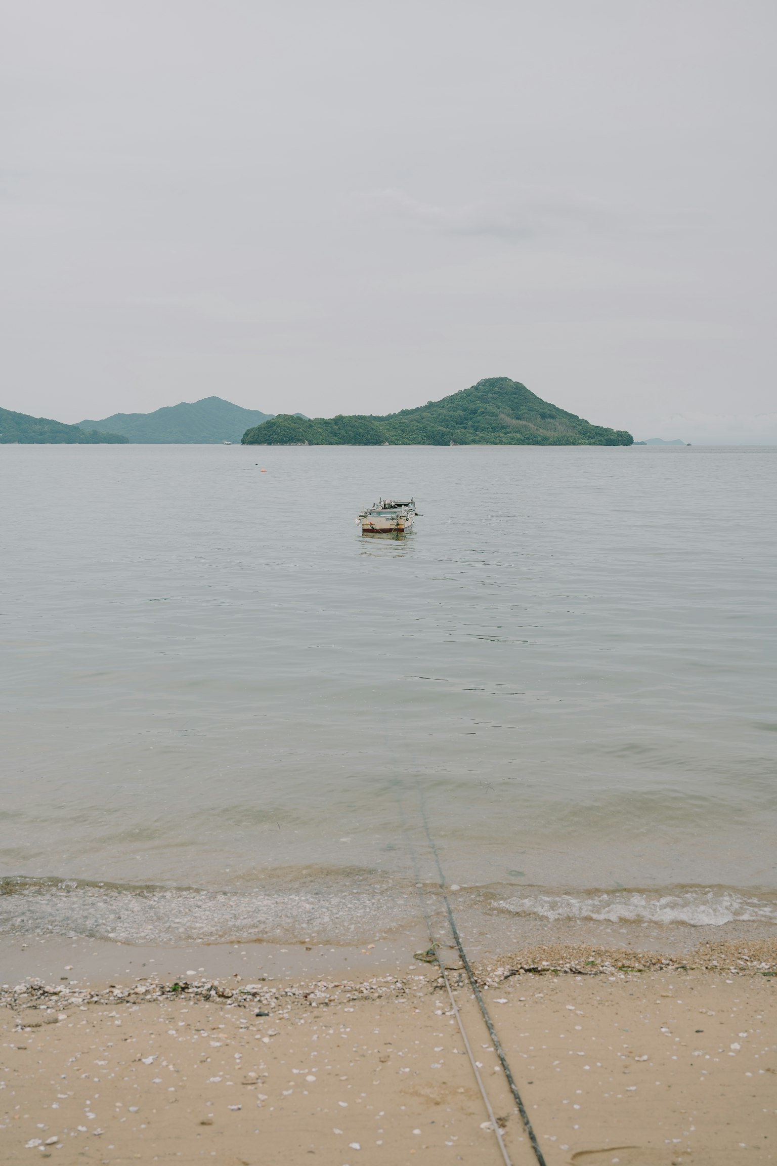 Vue de la mer calme avec un petit bateau et des îles en arrière-plan